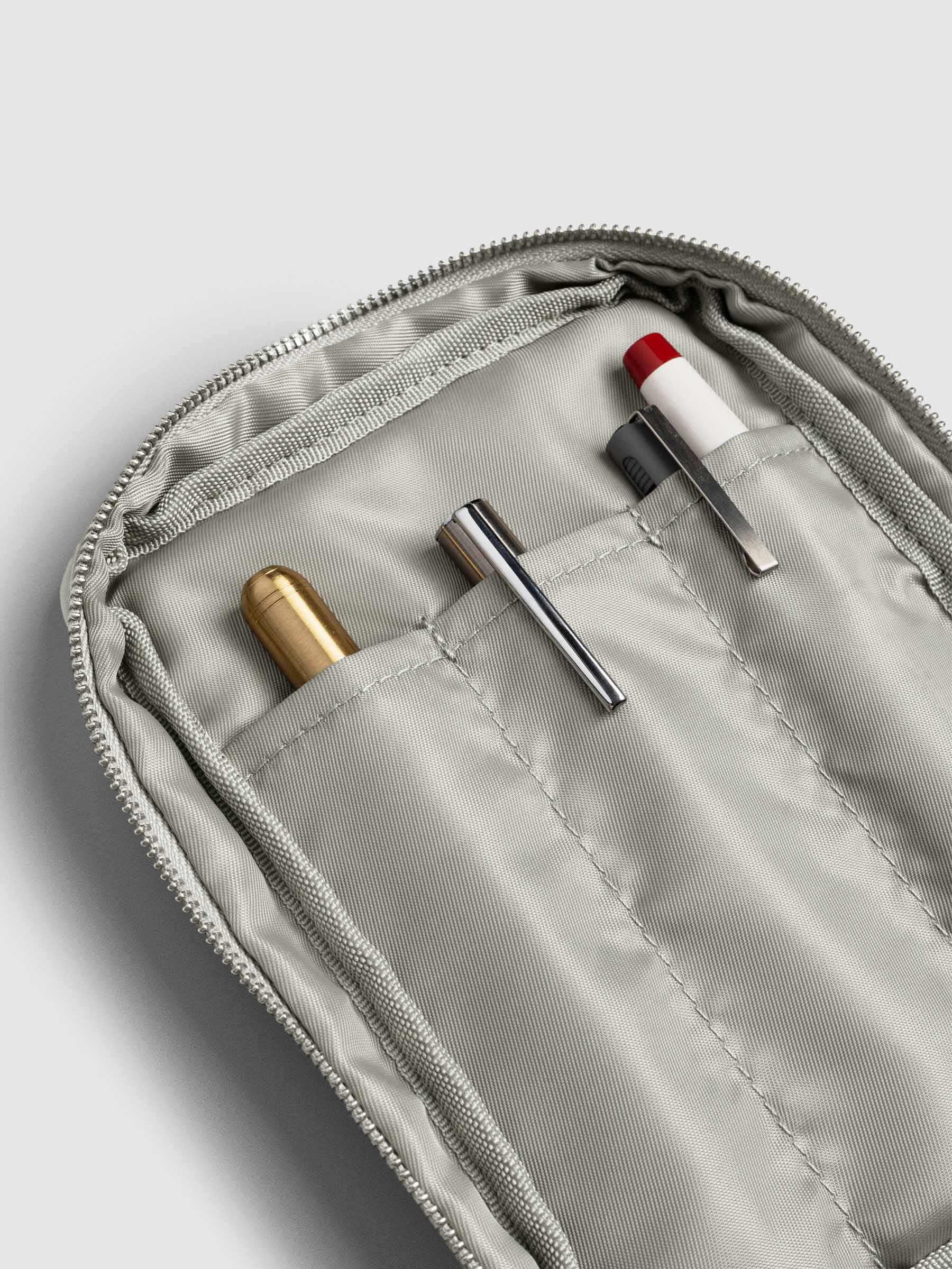 Close up angled view of the interior pen pocket of Fountain Pen Travel Case in Ristretto. There are four pens stored inside the pockets including brass, silver, and white pens.