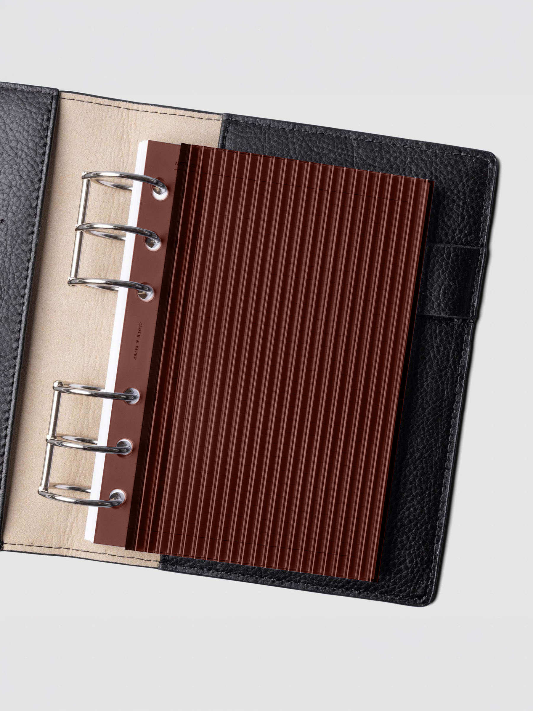 Bordeaux fluted planner dashboard in A6 size shown in a black leather six ring agenda with silver rings.