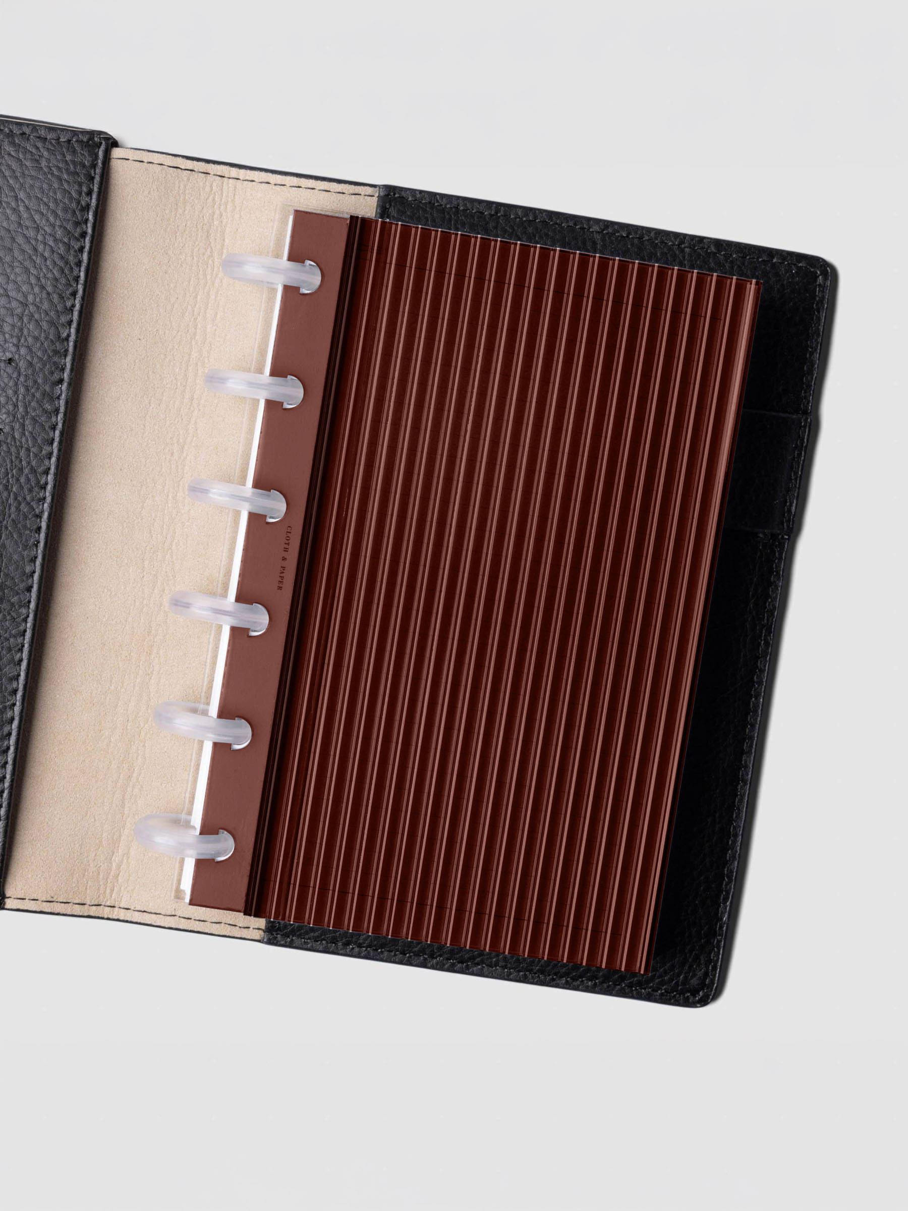 Bordeaux fluted planner dashboard in CP Petite size shown in a black leather discbound cover with clear discs.