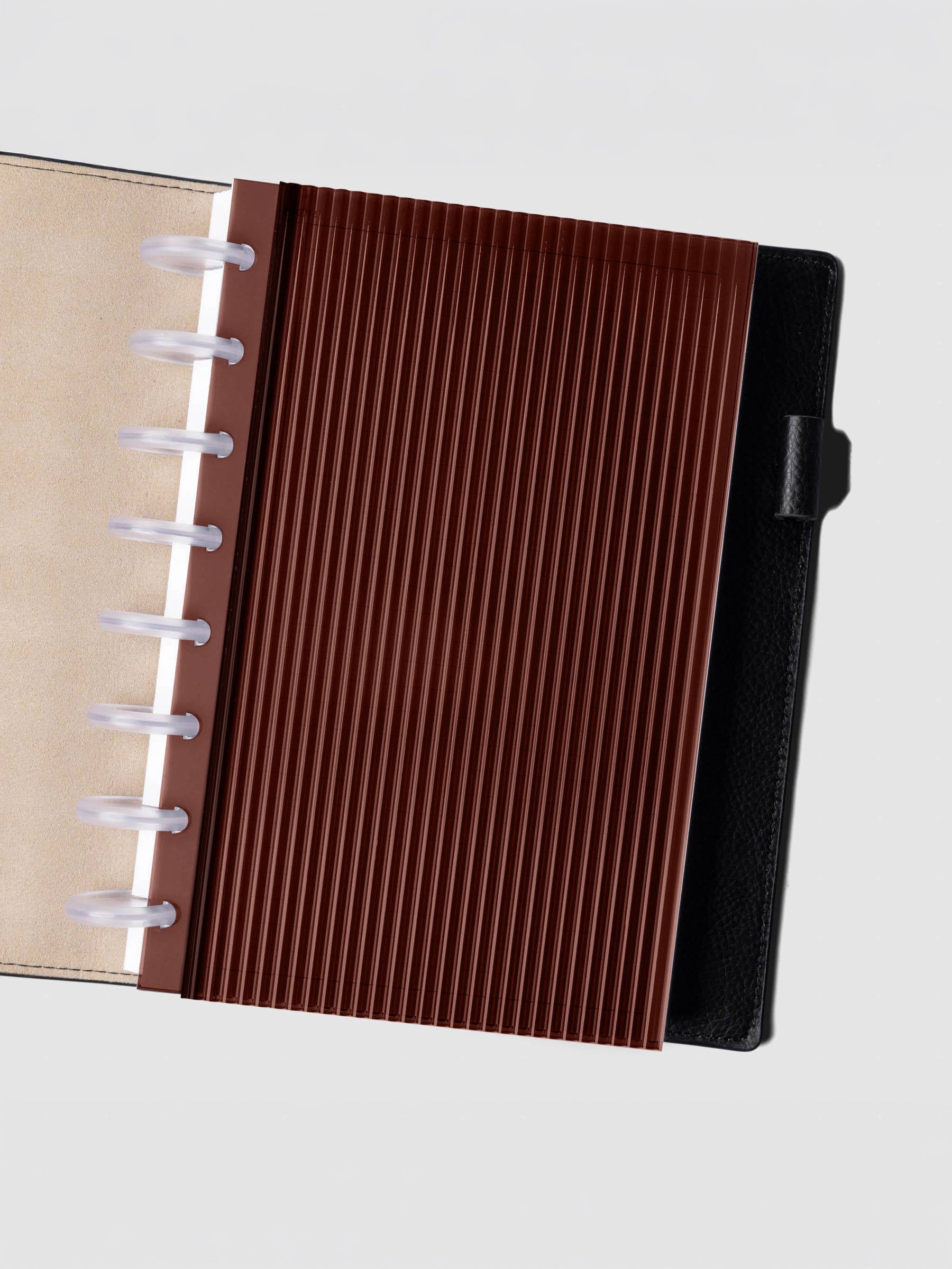 Bordeaux fluted planner dashboard in Half Letter size shown in a black leather discbound cover with clear discs.