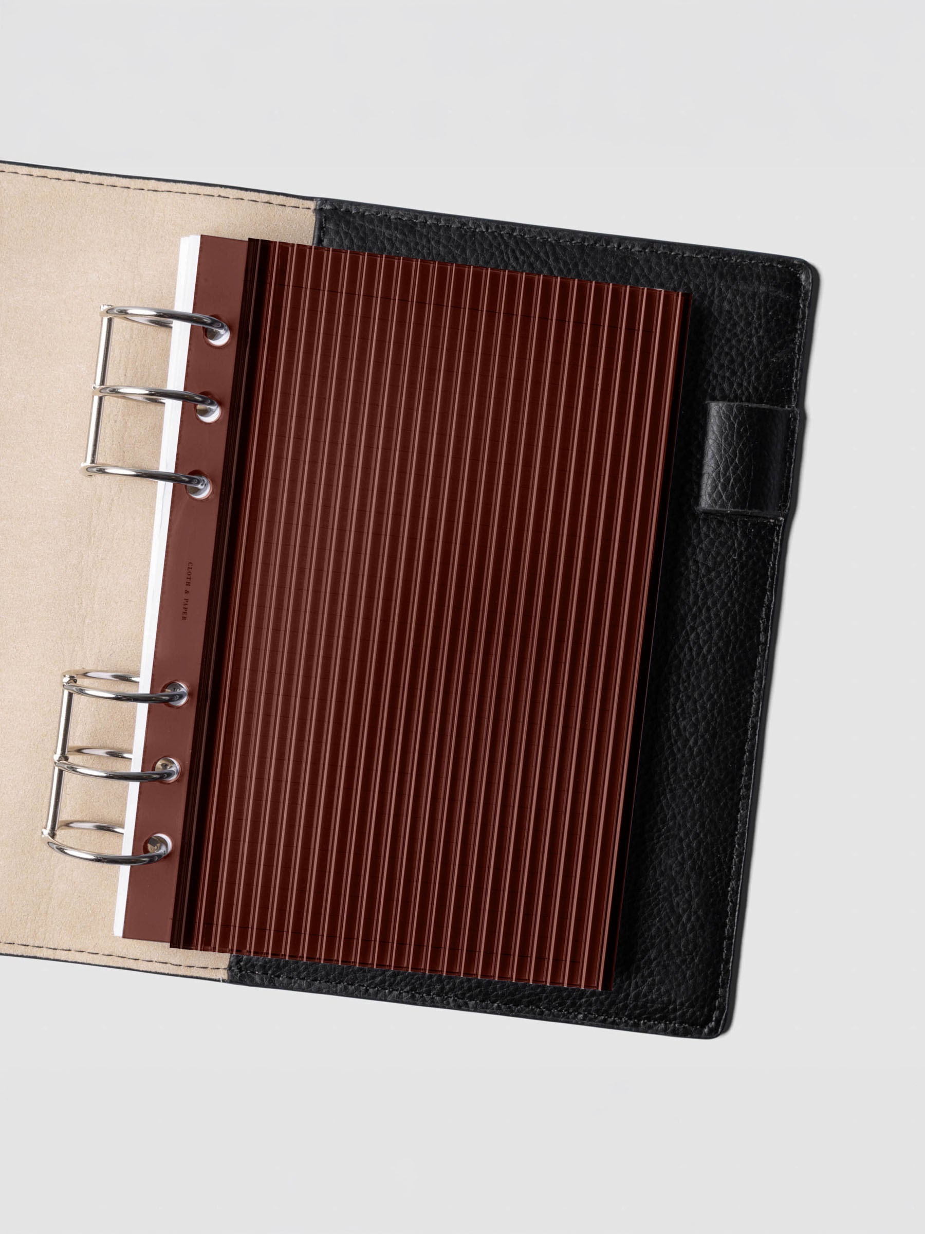 Bordeaux fluted planner dashboard in Personal Wide size shown in a black leather six ring agenda with silver rings.