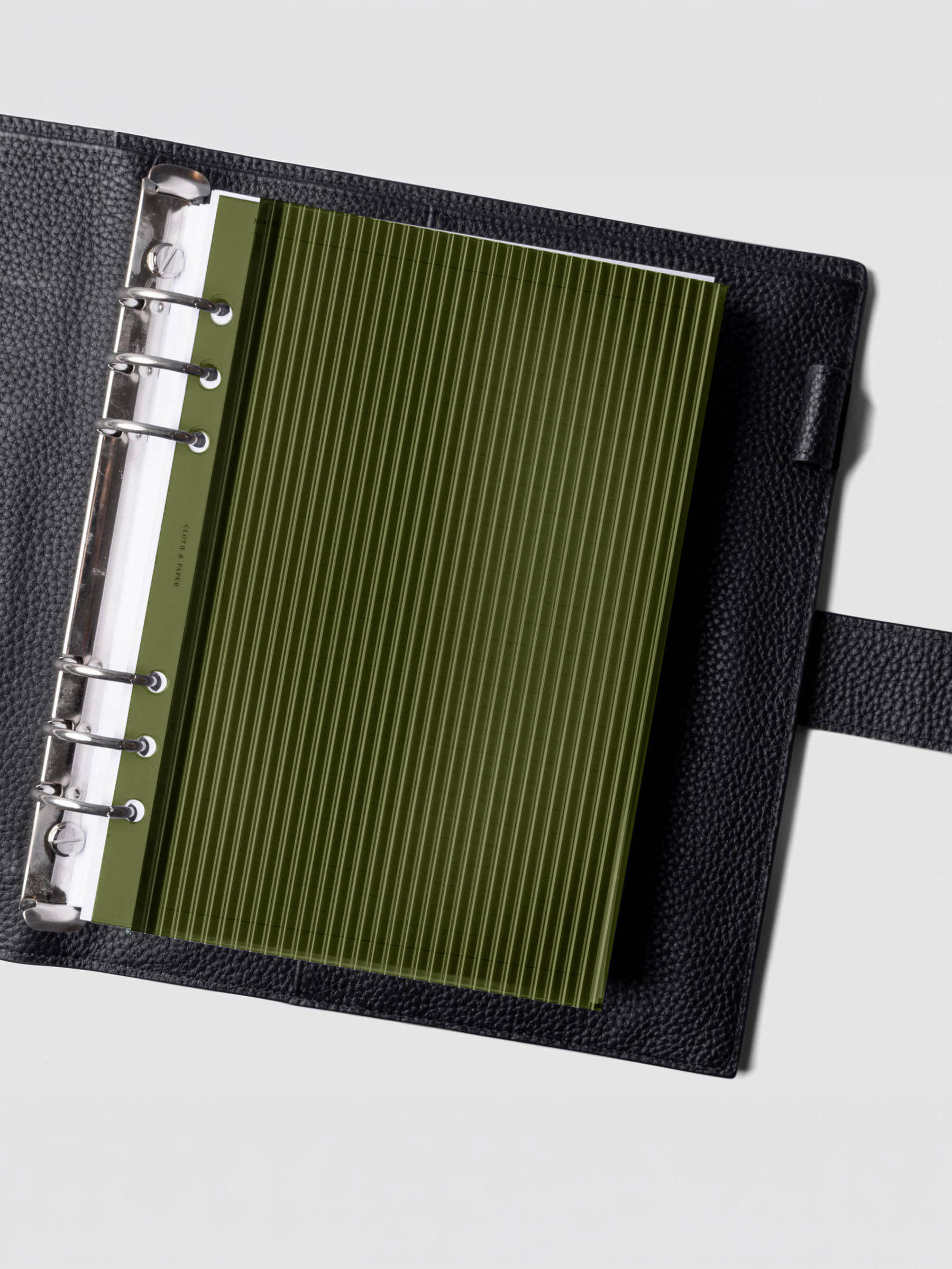 Olive fluted planner dashboard in A5 size shown in a black leather six ring agenda with silver rings.