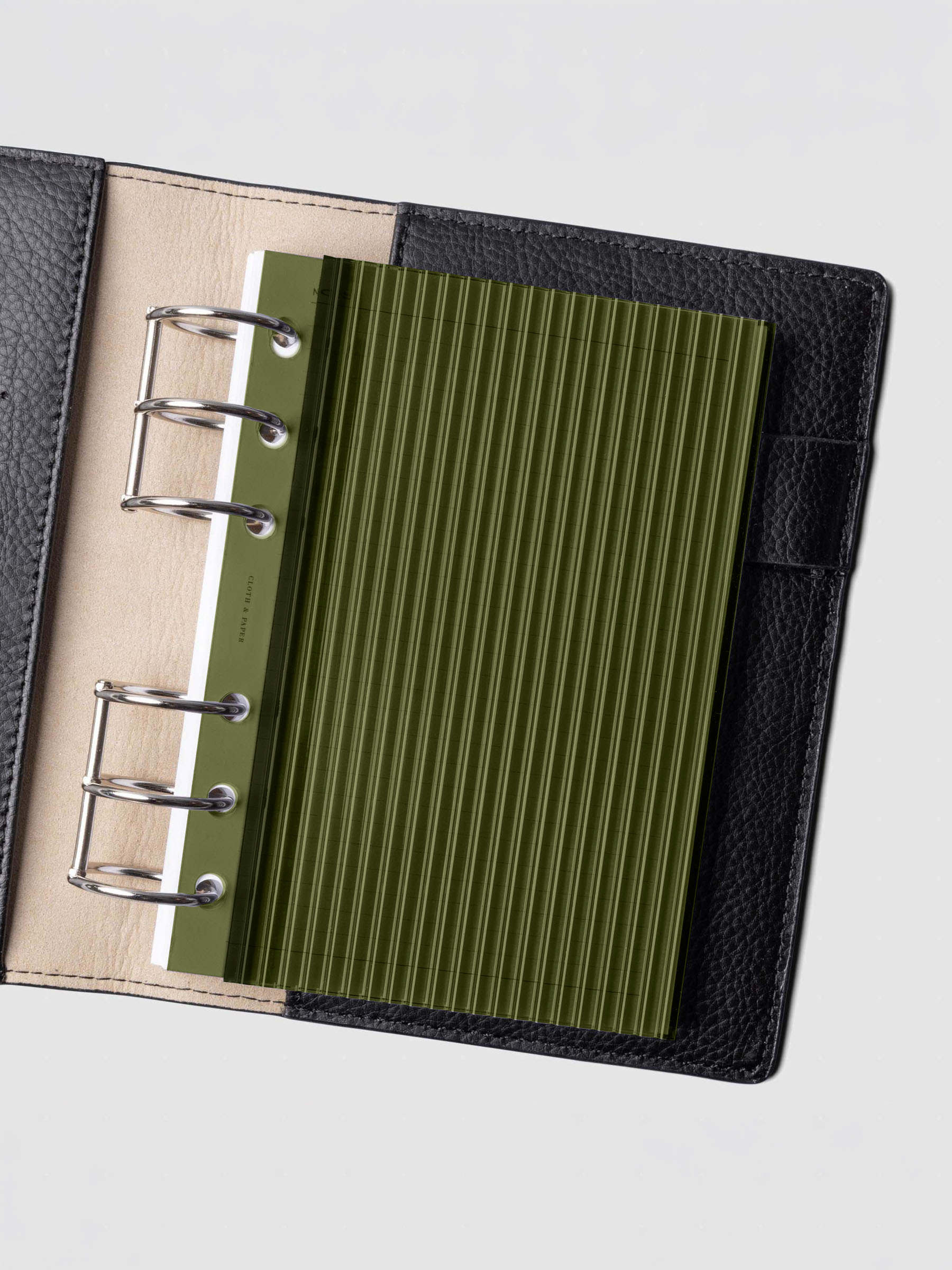 Olive fluted planner dashboard in A6 size shown in a black leather six ring agenda with silver rings.