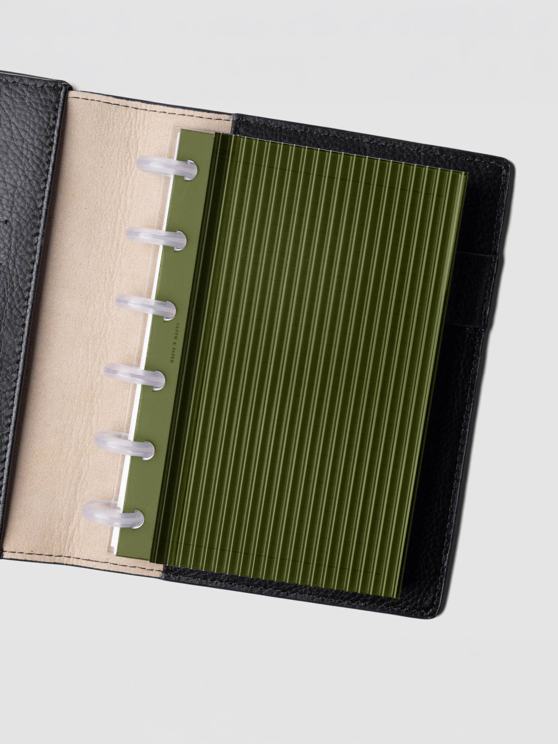 Olive fluted planner dashboard in CP Petite size shown in a black leather discbound cover with clear discs.