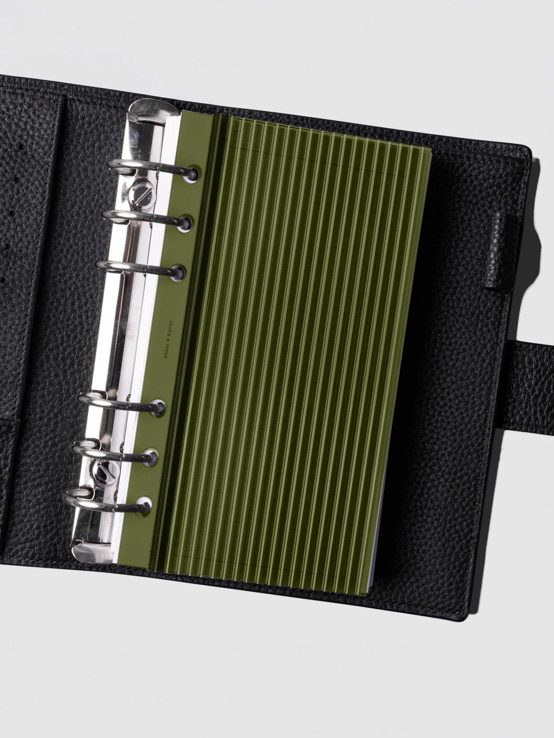 Olive fluted planner dashboard in Personal size shown in a black leather six ring agenda with silver rings.