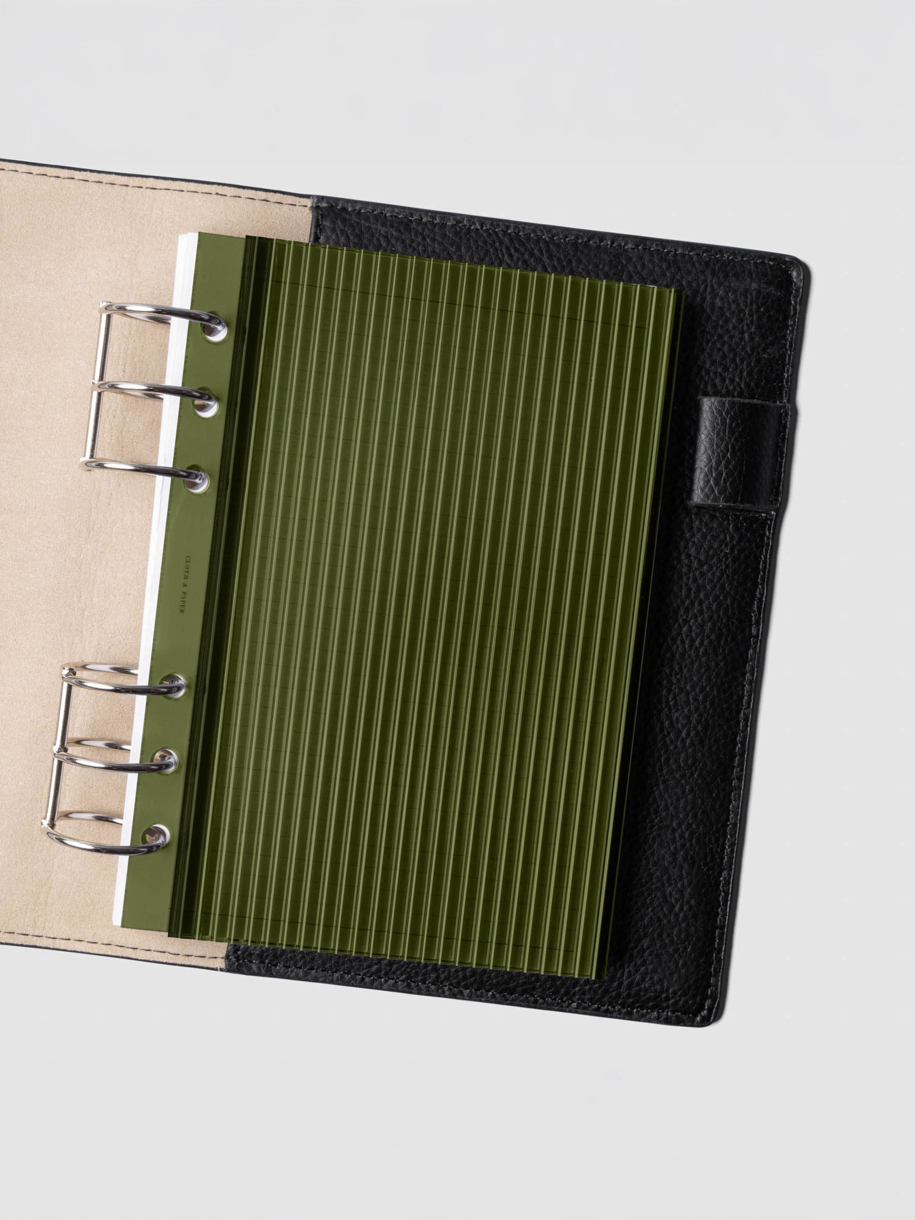 Olive fluted planner dashboard in Personal Wide size shown in a black leather six ring agenda with silver rings.