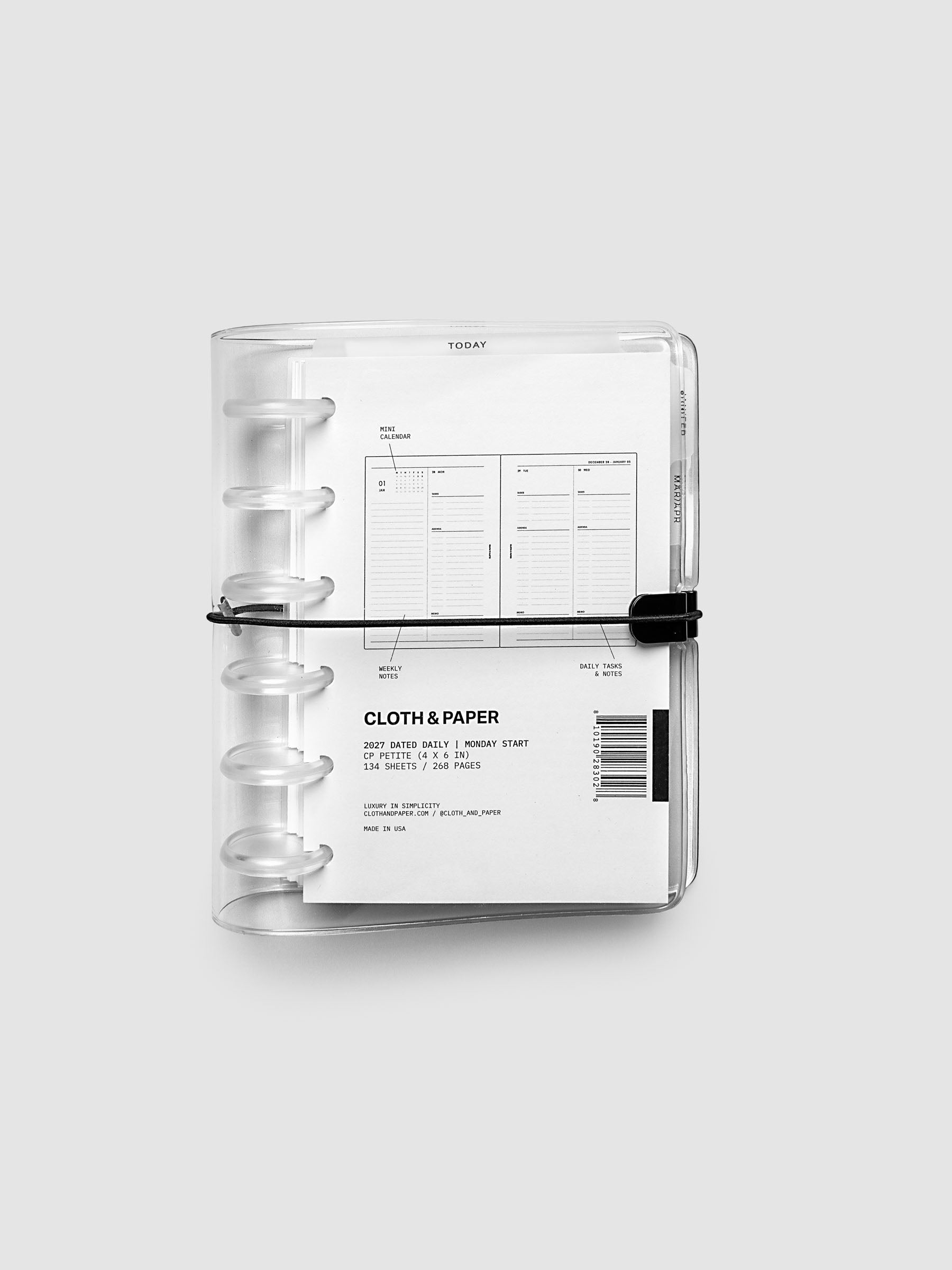 Closed clear vinyl planner cover with clear 6-disc binding and a black elastic closure, front page displaying a labeled weekly spread with mini calendar, weekly notes, and daily tasks callouts, CP Petite 6-Disc Punch size