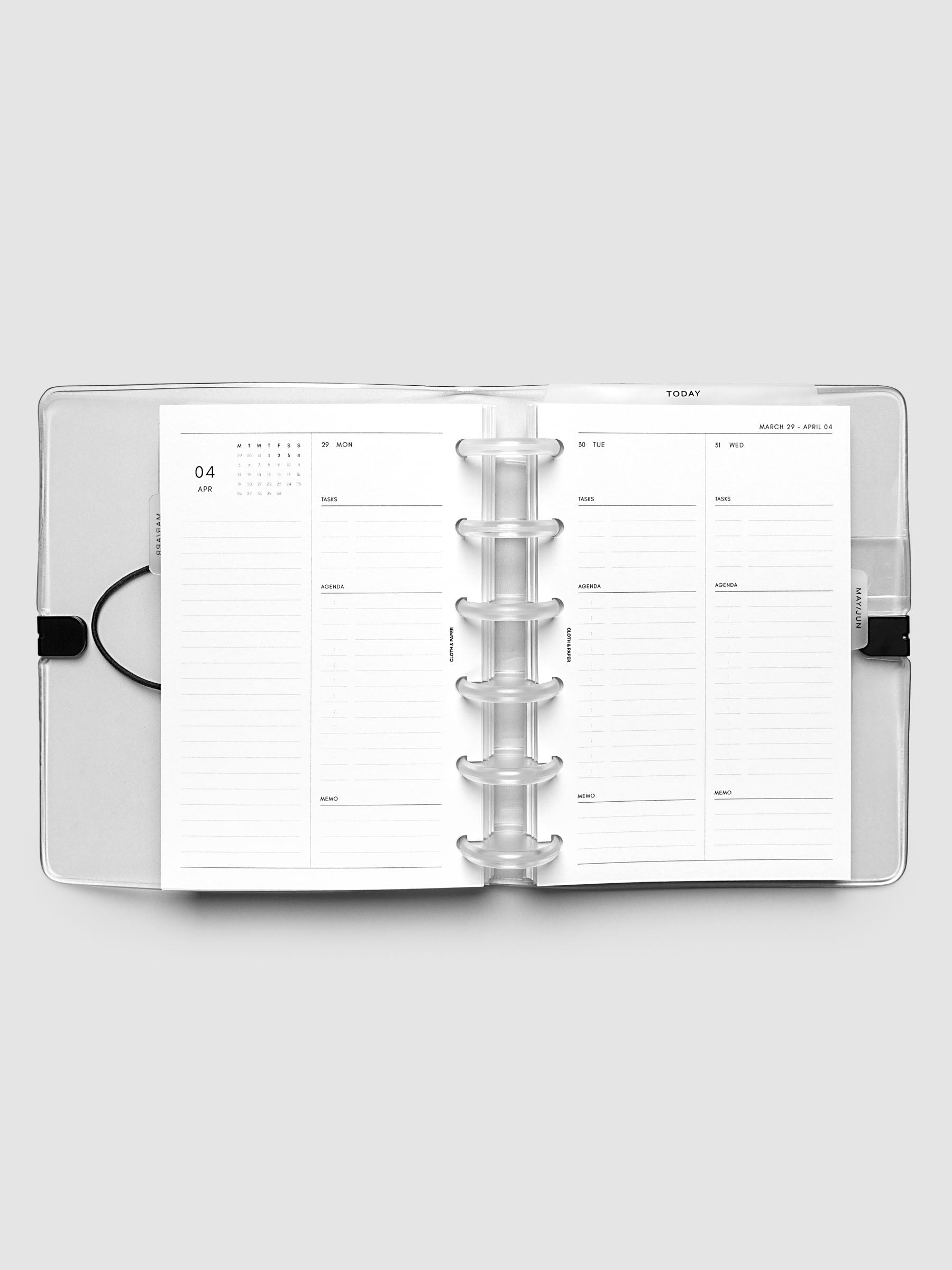 Flat lay of an open planner with clear 6-disc binding at the center, a Monday through Wednesday spread across two facing pages with a mini monthly calendar, daily tasks, agenda, and memo sections, CP Petite 6-Disc Punch size
