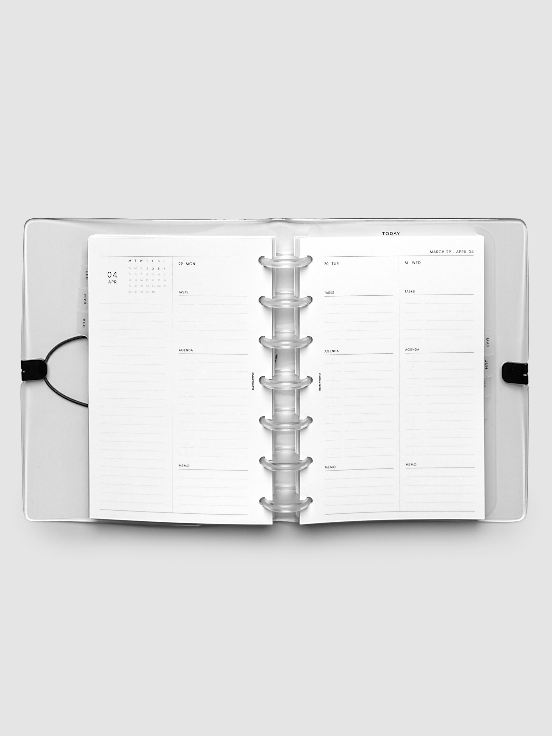 Flat lay of an open planner with clear 7-disc binding at the center, a Monday through Wednesday spread across two facing pages with a mini monthly calendar, daily tasks, agenda, and memo sections, HP Mini 7-Disc Punch size