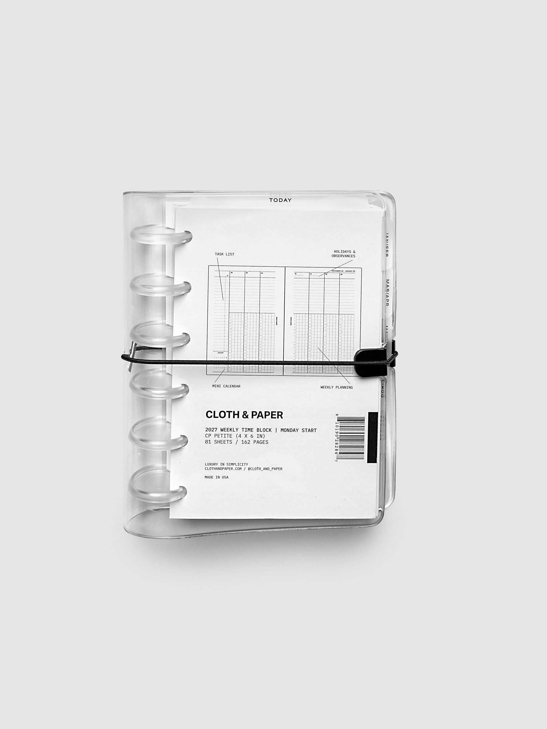 Closed clear vinyl planner cover with clear 6-disc binding and a black elastic closure, front page displaying a labeled weekly time block spread with task list, holidays and observances, mini calendar, and weekly planning callouts, CP Petite 6-Disc Punch size