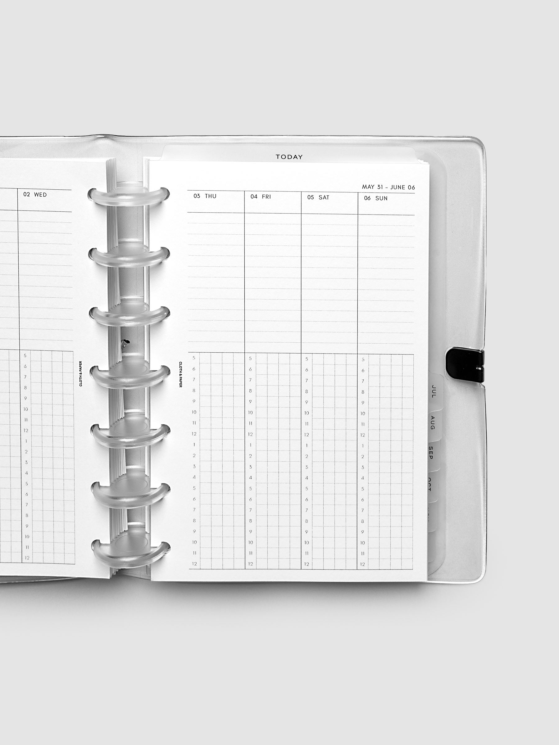 Close-up of an open planner with clear 7-disc binding, weekly time block spread showing Thursday through Sunday columns with a task list above and an hourly grid below, tabbed monthly dividers visible at the edge, HP Mini 7-Disc Punch size