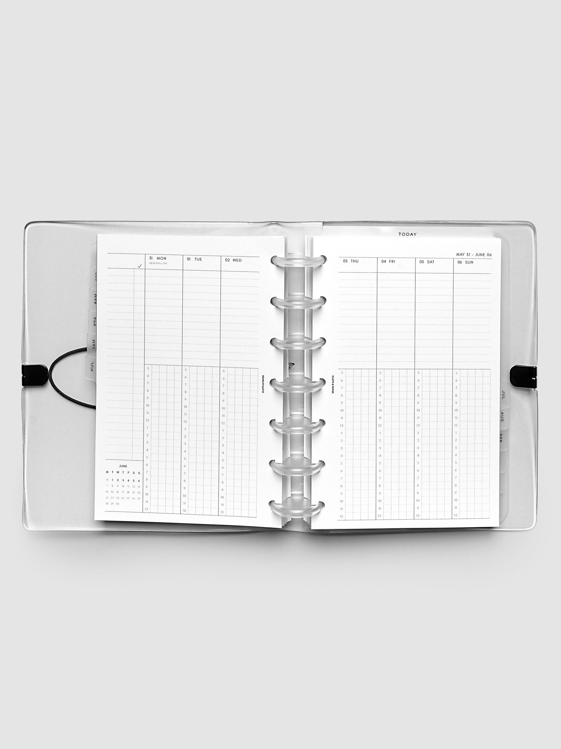 Flat lay of an open planner with clear 7-disc binding at the center, a Monday through Sunday weekly time block spread across two facing pages with task lists, hourly grids, and a mini monthly calendar, HP Mini 7-Disc Punch size