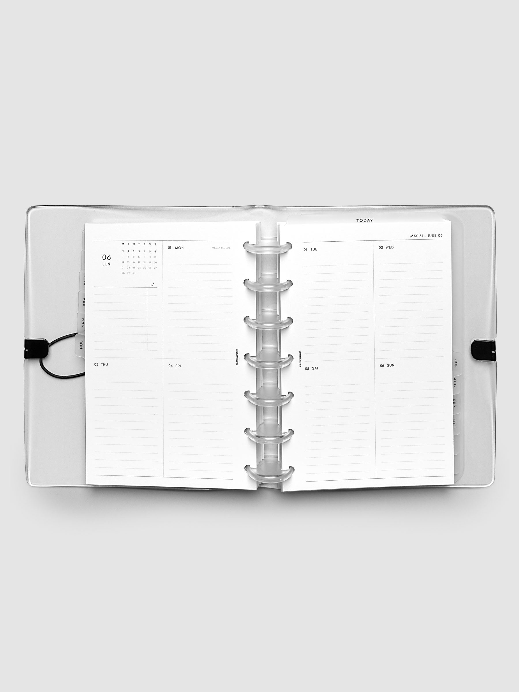 Flat lay of an open planner with clear 7-disc binding at the center, a Monday through Sunday weekly vertical spread across two facing pages with a mini calendar and lined daily sections, HP Mini 7-Disc Punch size