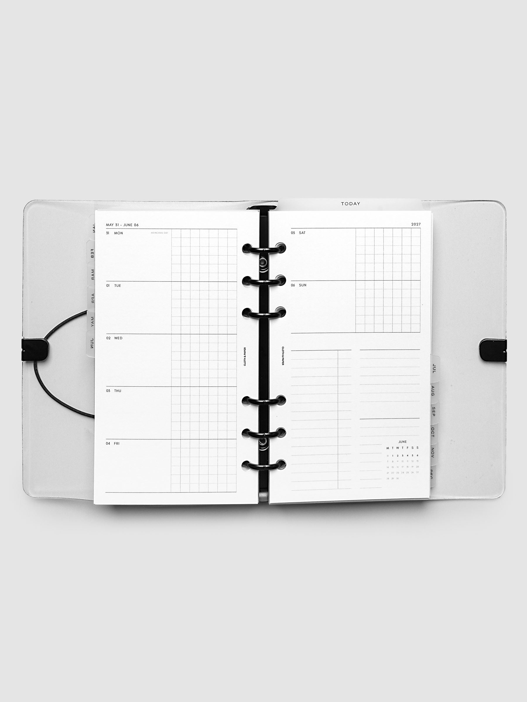 Flat lay of an open planner with black 6-ring binding at the center, a Monday through Sunday weekly horizontal spread across two facing pages with a tasks and notes section and mini calendar, Personal 6-Ring Punch size