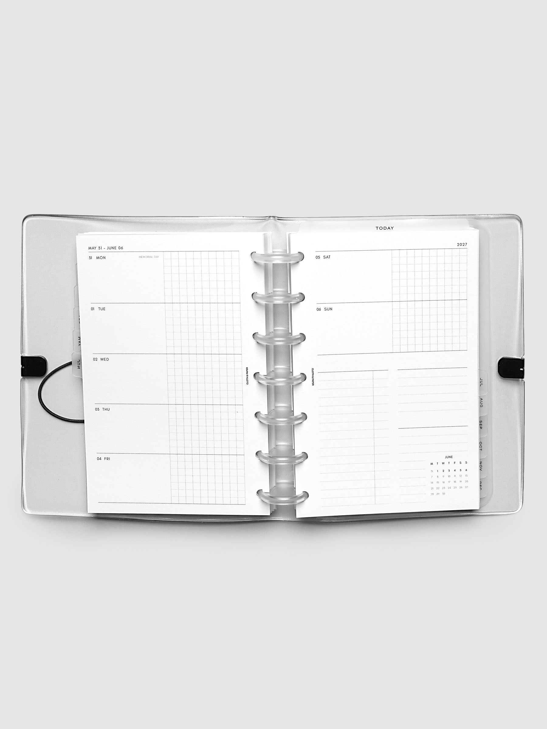 Flat lay of an open planner with clear 7-disc binding at the center, a Monday through Sunday weekly horizontal spread across two facing pages with a tasks and notes section and mini calendar, HP Mini 7-Disc Punch size