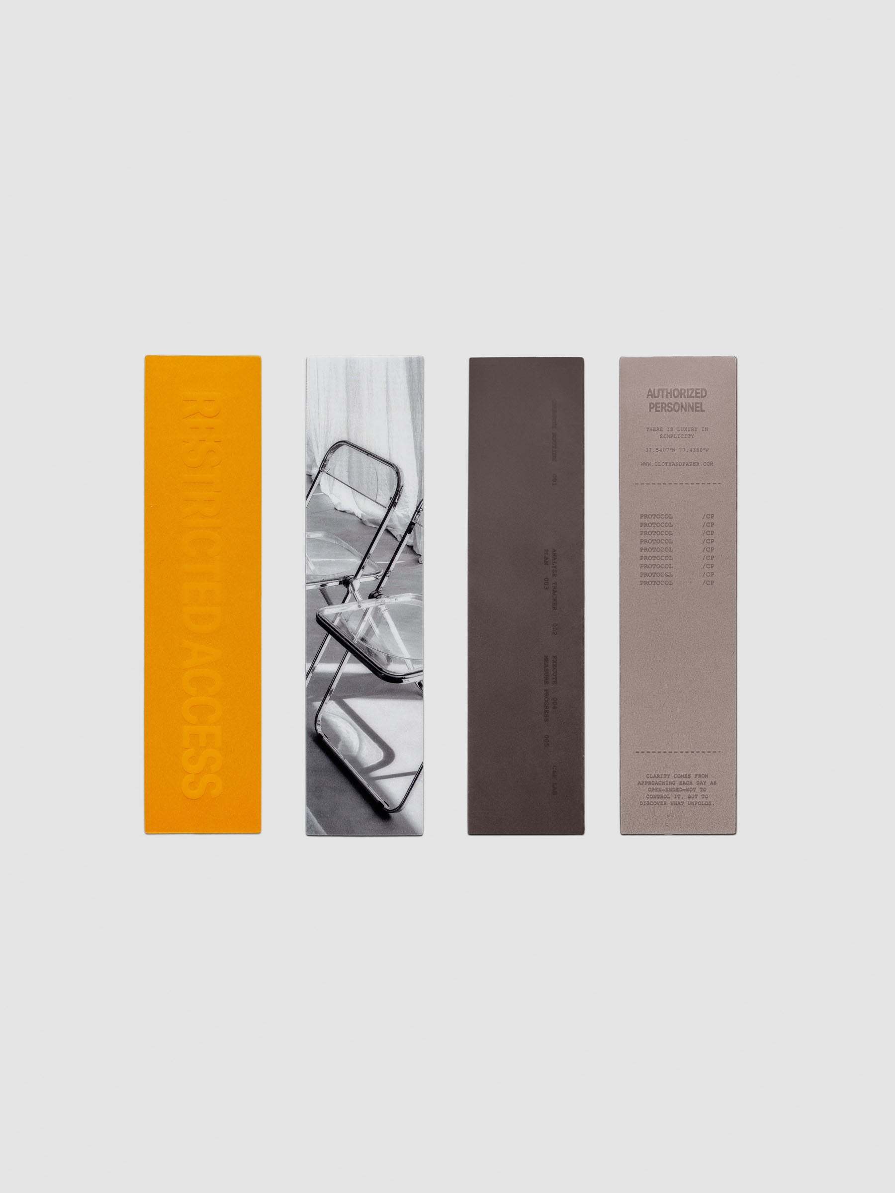 A set of four transparent thin bookmarks in orange, grey, black, and white printed with text or image designs.