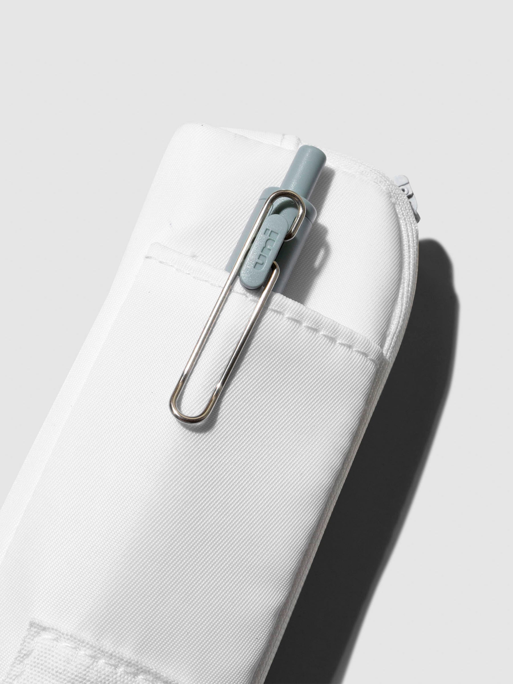 Uni Ball One pen displayed inside the external pocket of a notebook pouch. Color shown is Le Blanc.