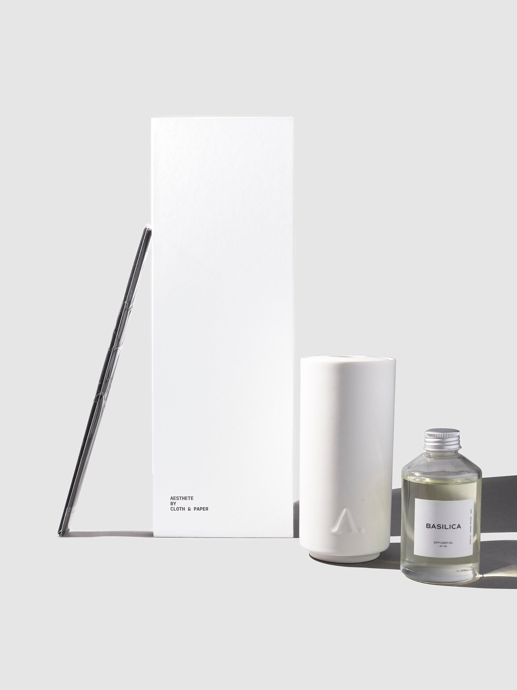 Basilica Diffuser, Cloth and Paper. Diffuser vessel, reeds, Basilica oil, and packaging displayed on a neutral background.