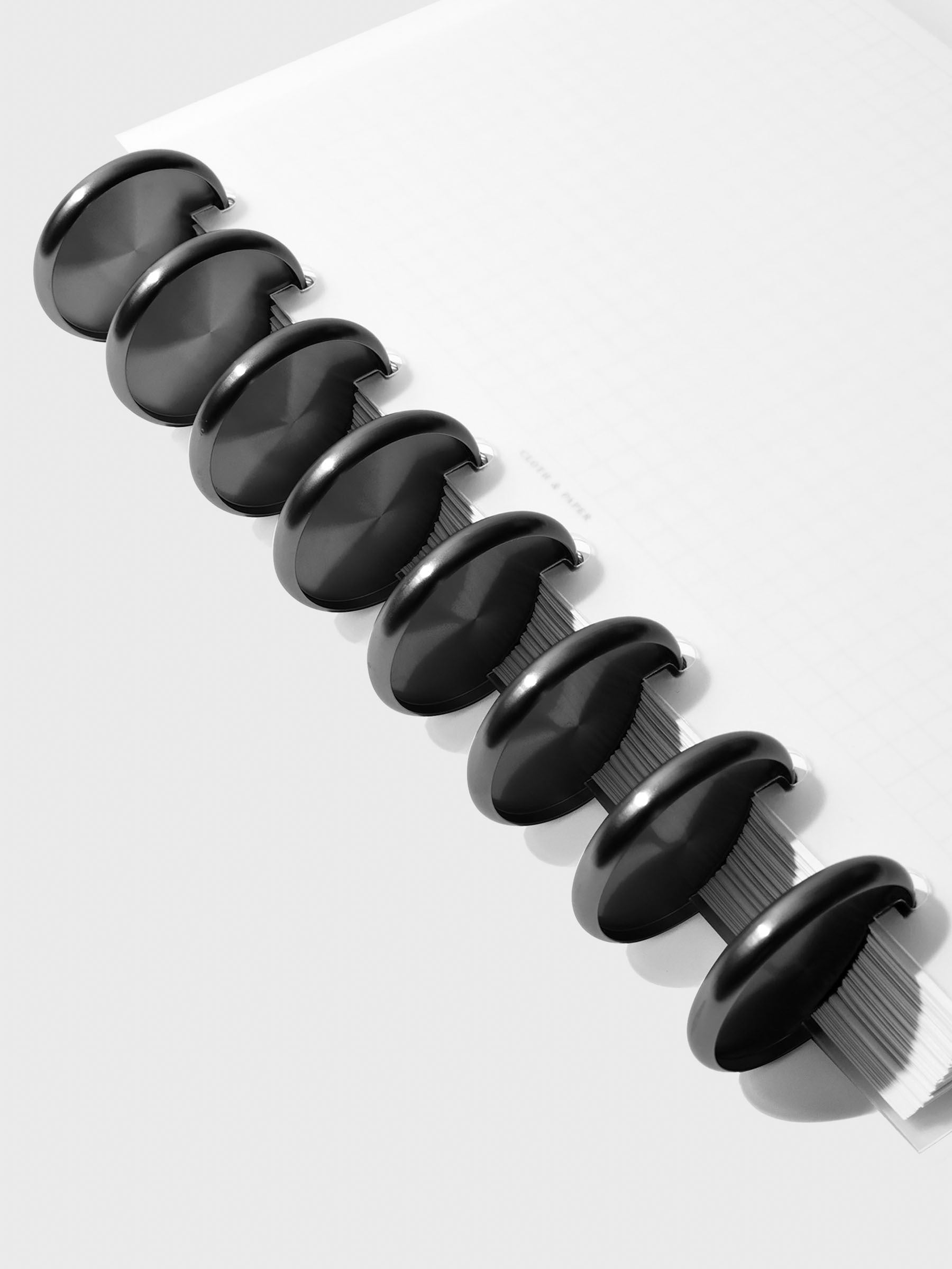Close-up of black aluminum planner discs, 1.5 inch size, set of nine stacked together.