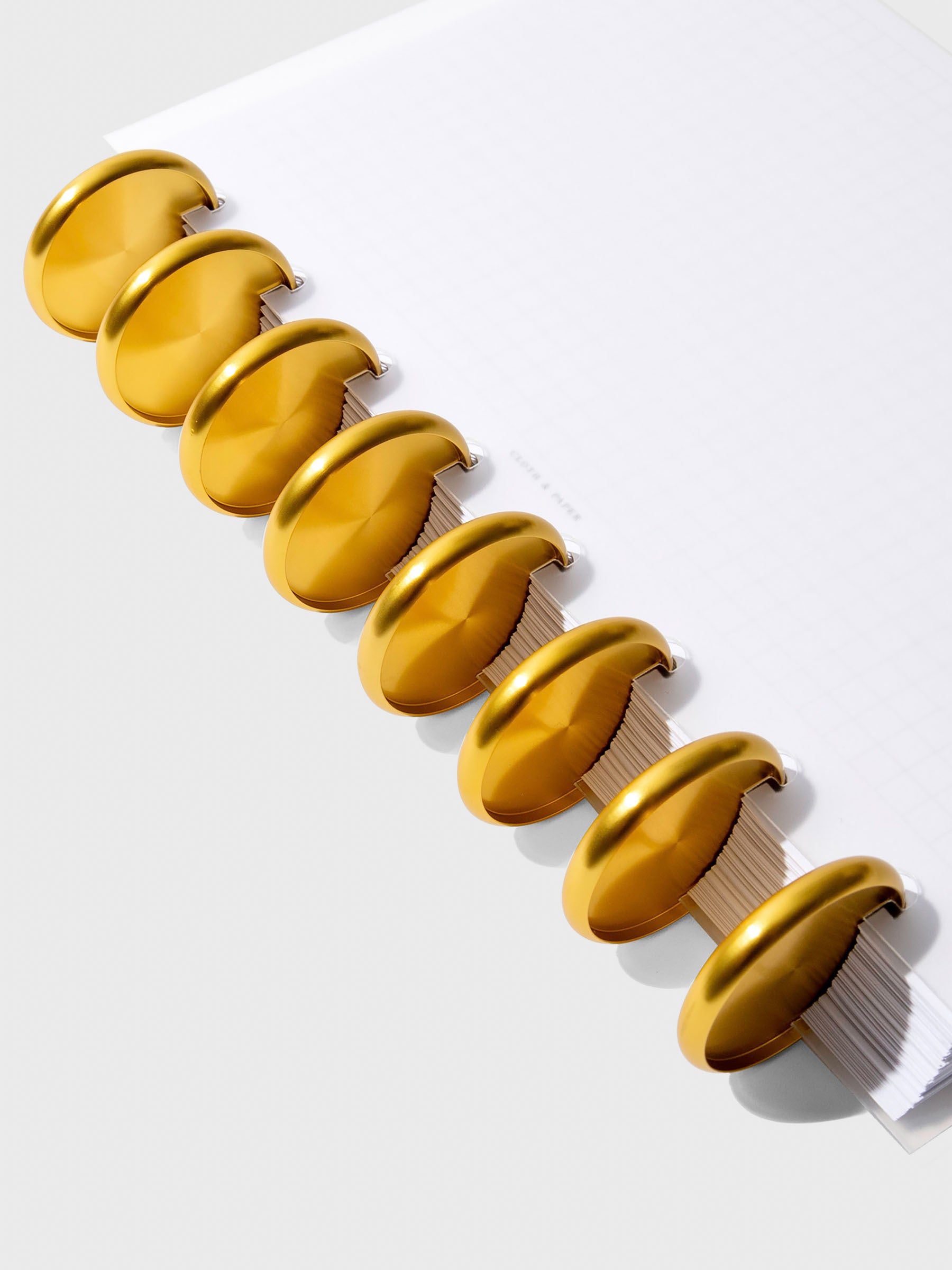 Close-up of gold aluminum planner discs, 1.5 inch size, set of nine stacked together.