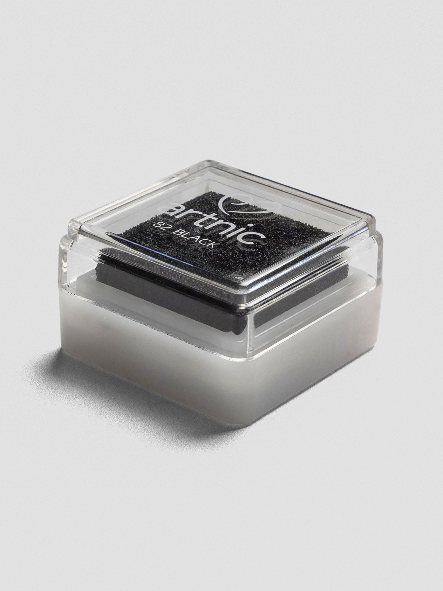 Angled side view of a closed Artnic stamp ink pad in black, showing the stackable clear lid and white base.