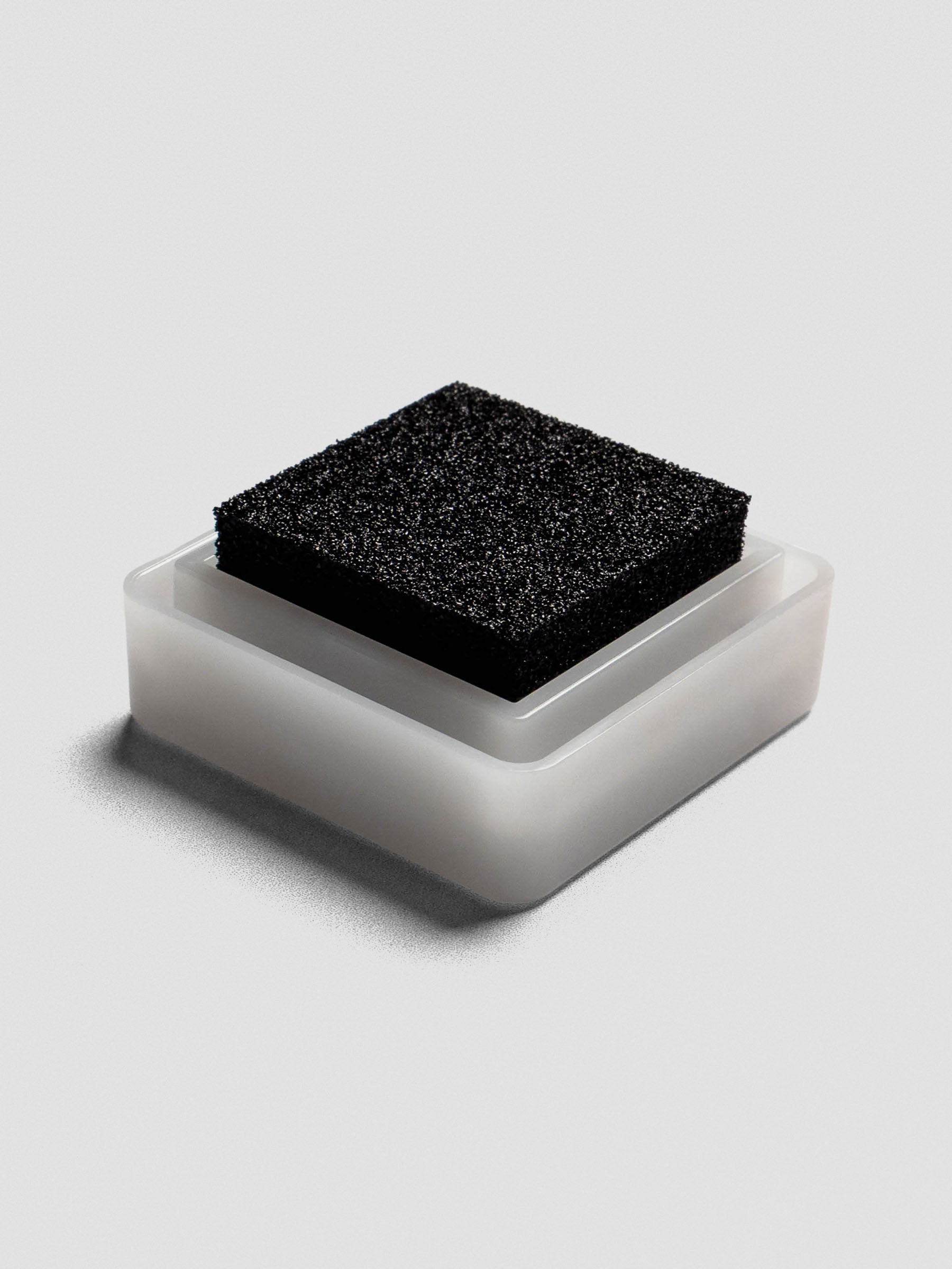 Close-up angled view of an Artnic stamp ink pad in black, showing the sponge texture with the clear lid removed.