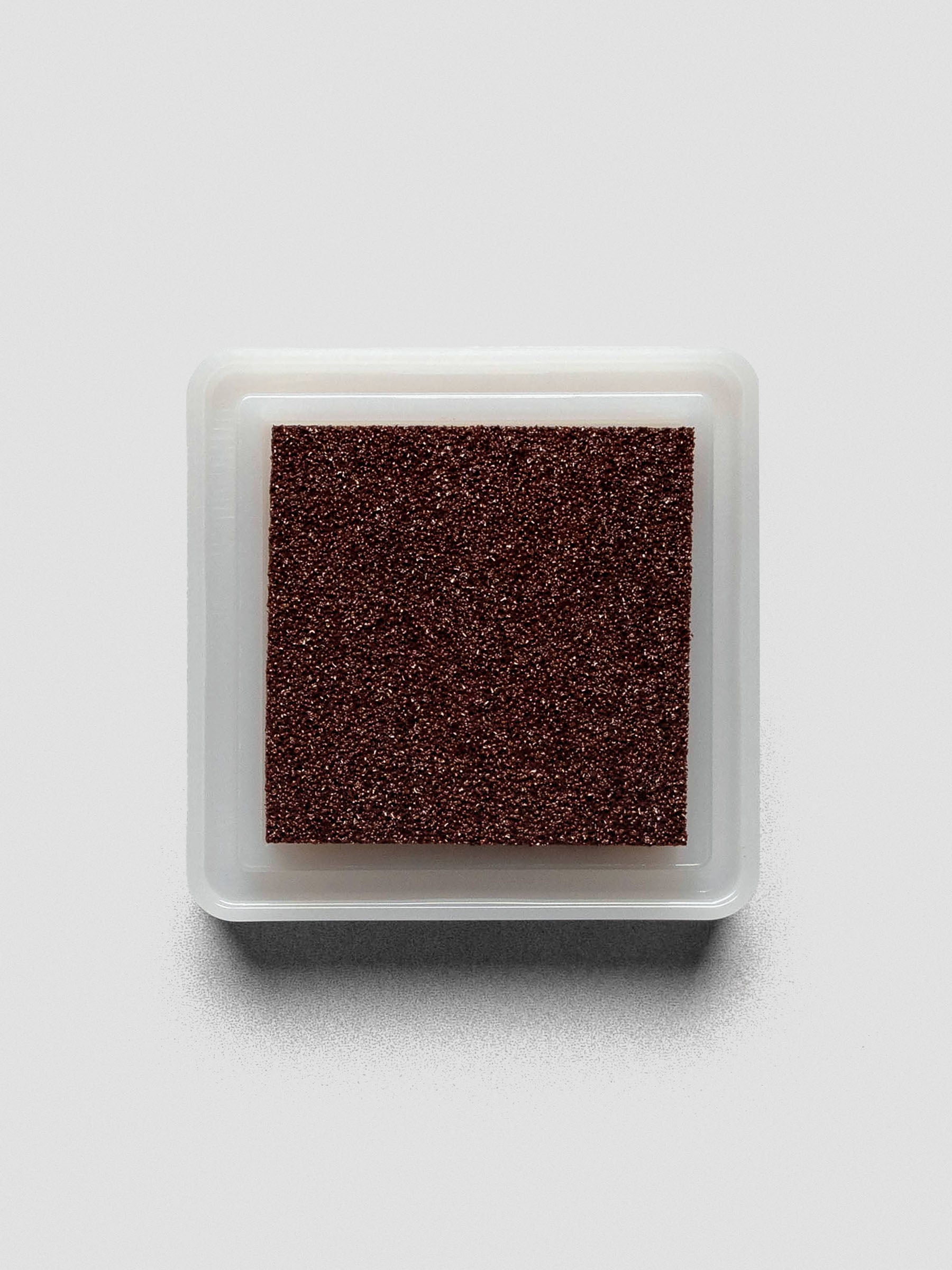 Overhead view of an open Artnic stamp ink pad in brown, highlighting the textured sponge surface.