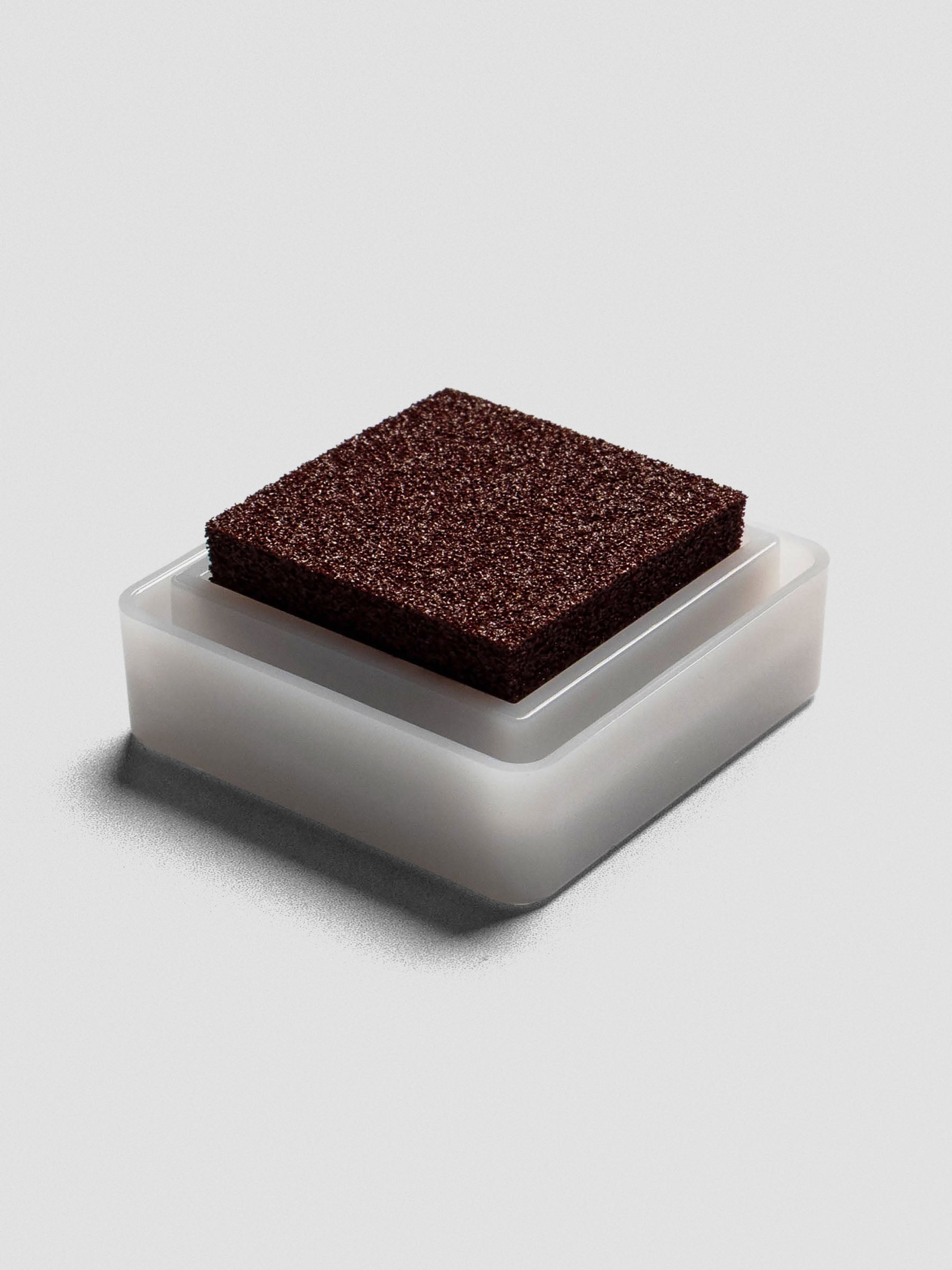 Angled view of an open Artnic stamp ink pad in brown, highlighting the textured sponge surface.