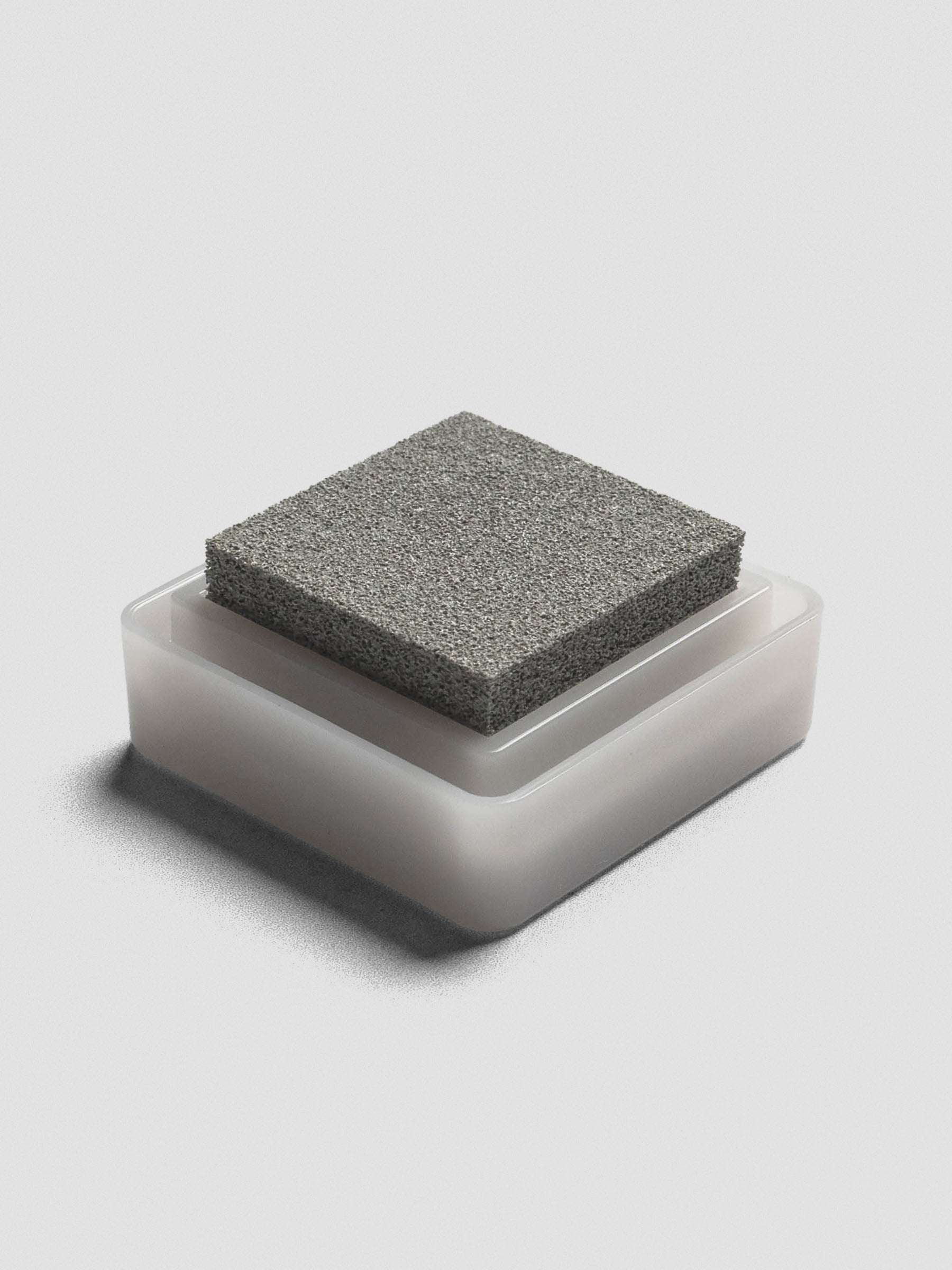 Gray Artnic ink pad without lid, angled view of textured ink surface and white base. 