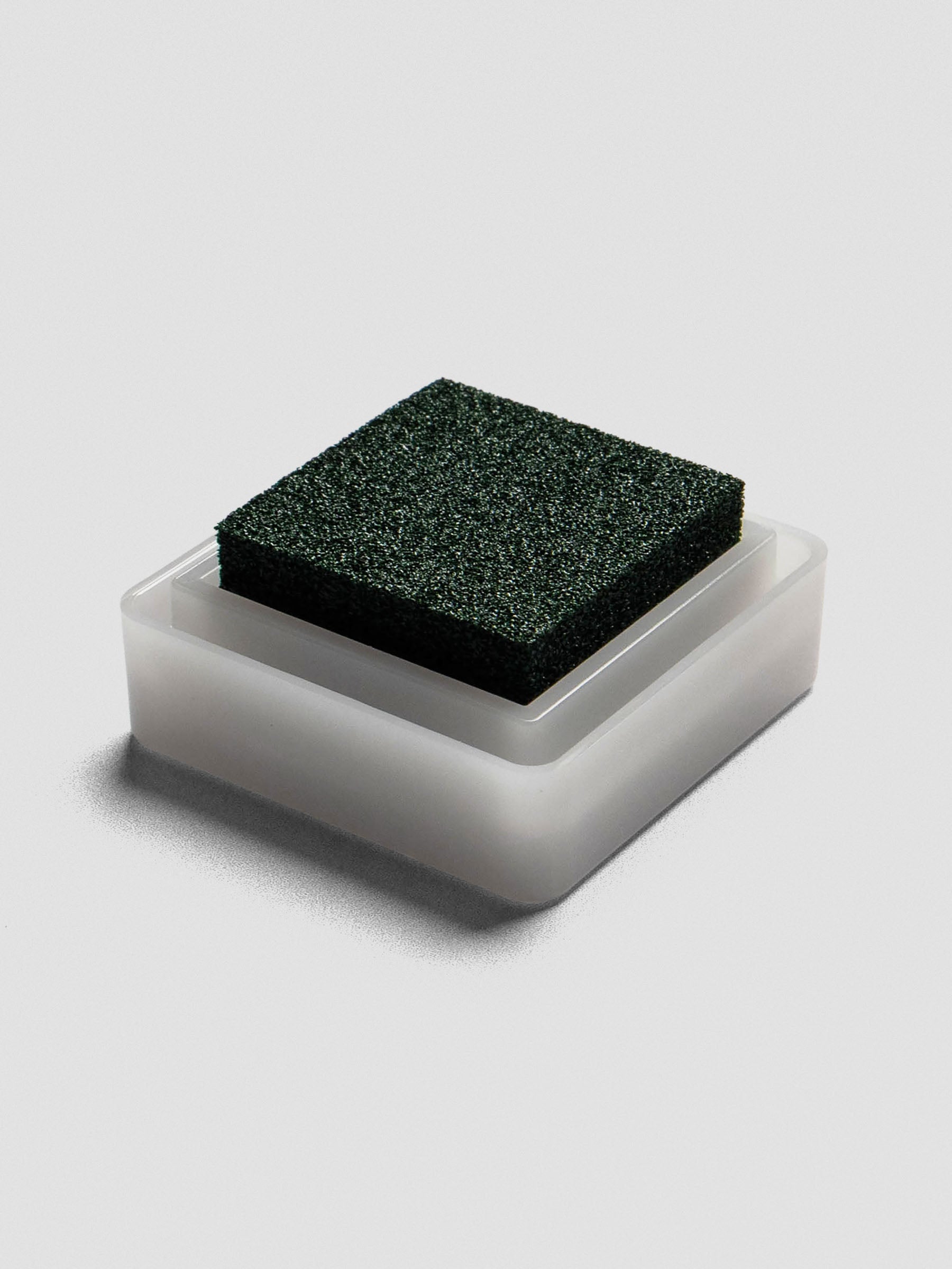 Side view of open Evergreen ink pad with green foam pad resting in white plastic base.