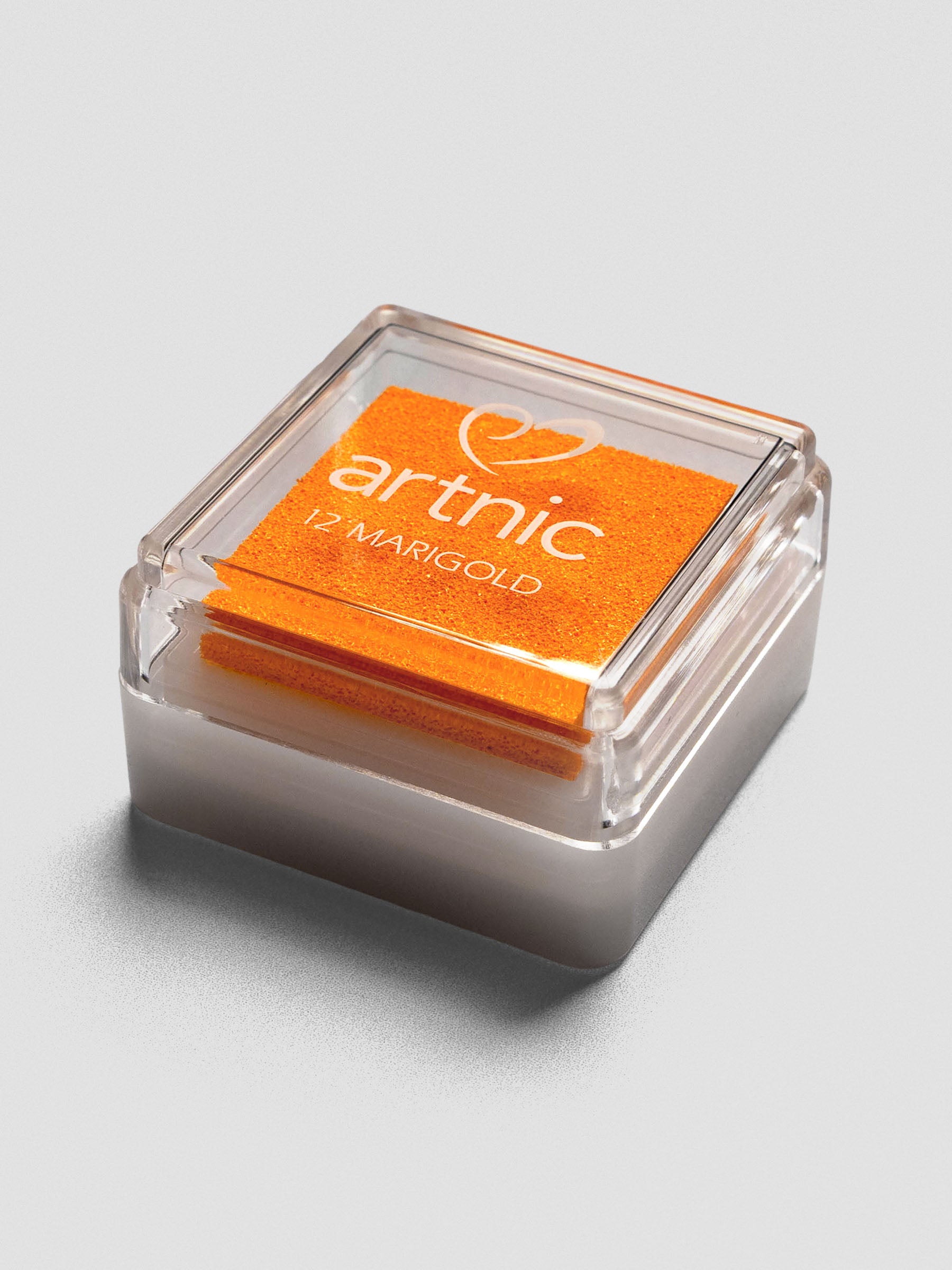 Angled view of Artnic Marigold ink pad showing clear lid, orange foam pad, and stackable white plastic base.