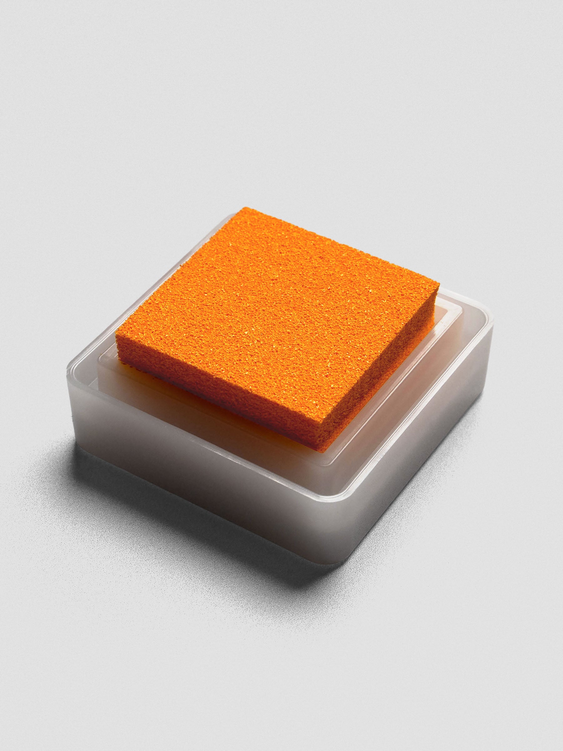 Side view of open Marigold ink pad with vibrant orange foam pad in white plastic base.