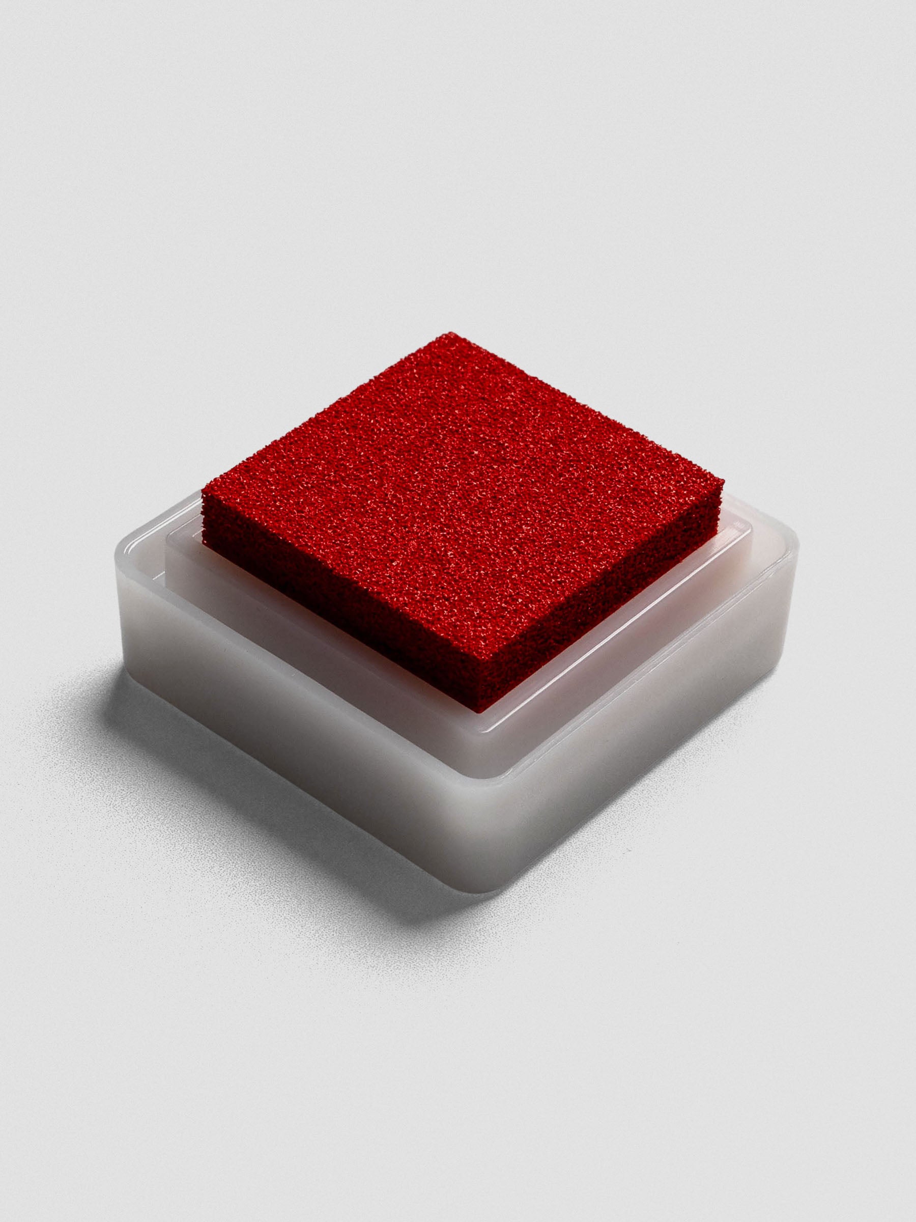 Red Artnic ink pad without lid, angled view of textured ink surface and white base.