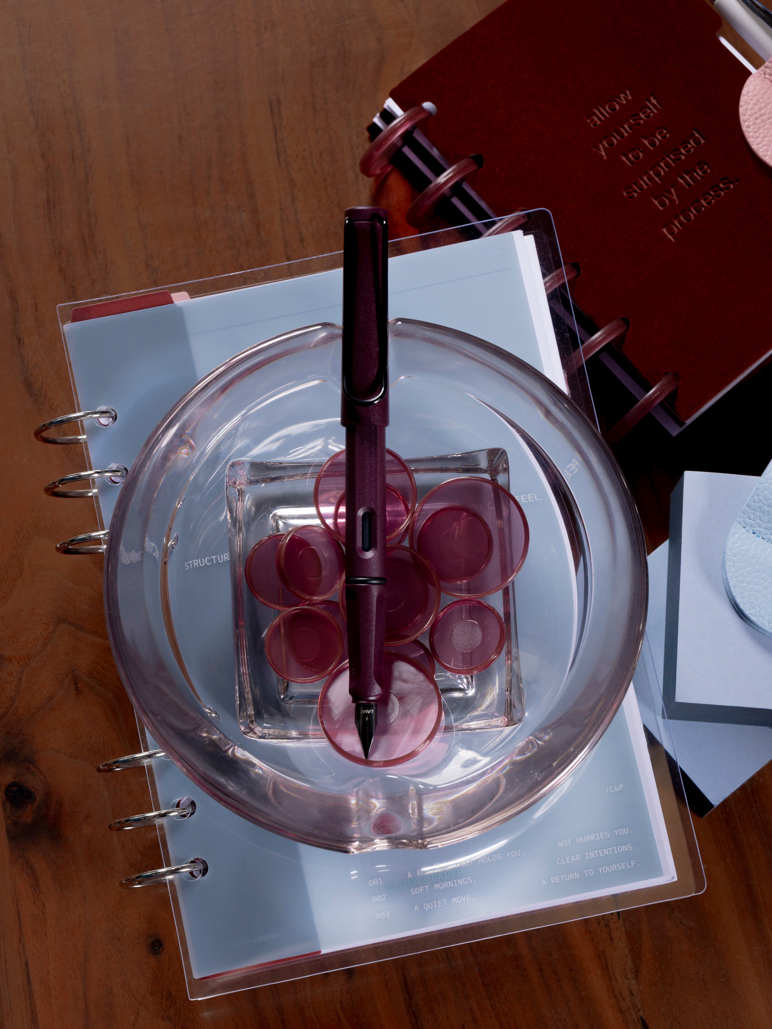 LAMY Safari Fountain Pen in the color Scarlett with shown with the cap off on top of an assortment of products on a table. 