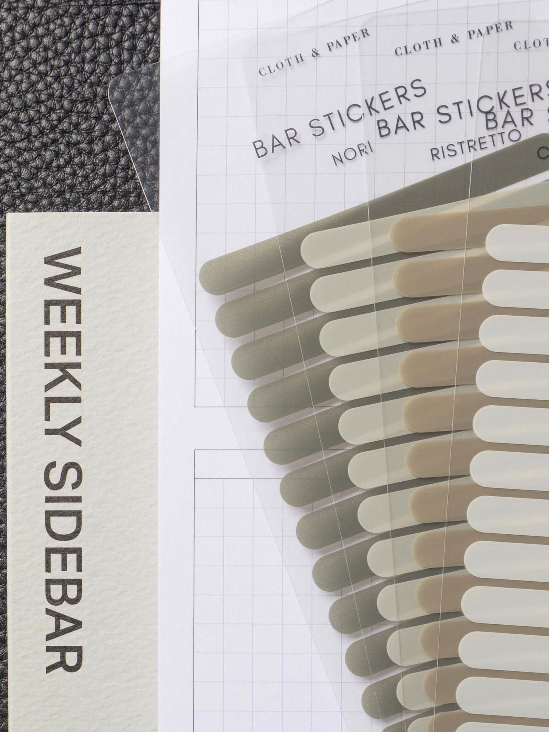 Set of four sticker sheets layered over each other inside a black leather planner. A Long Weekly Sidebar sticky note is visible beneath everything.