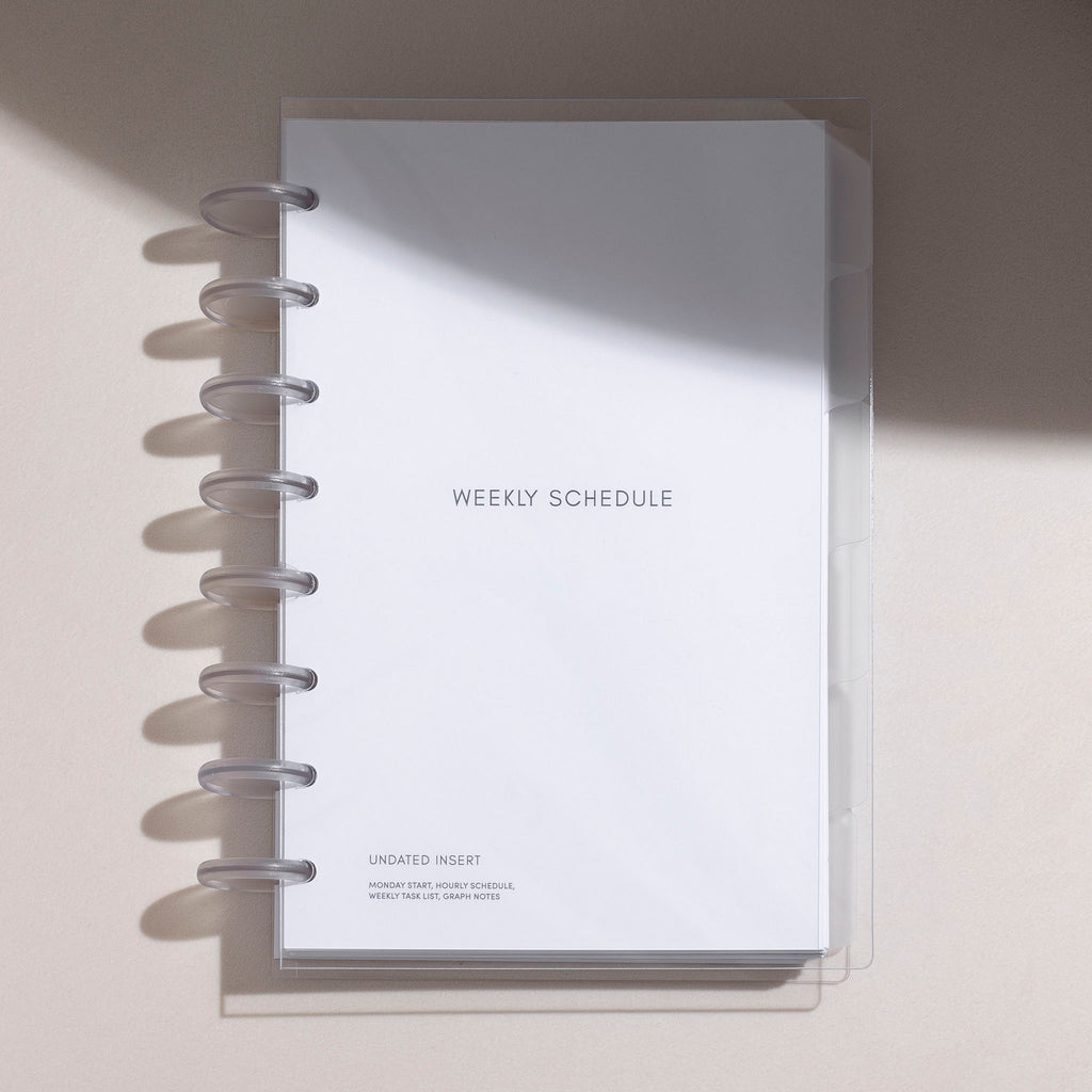 Half letter-sized Beginner Planner Bundle enclosed in a clear vinyl cover, resting on a white table with subtle shadows. 