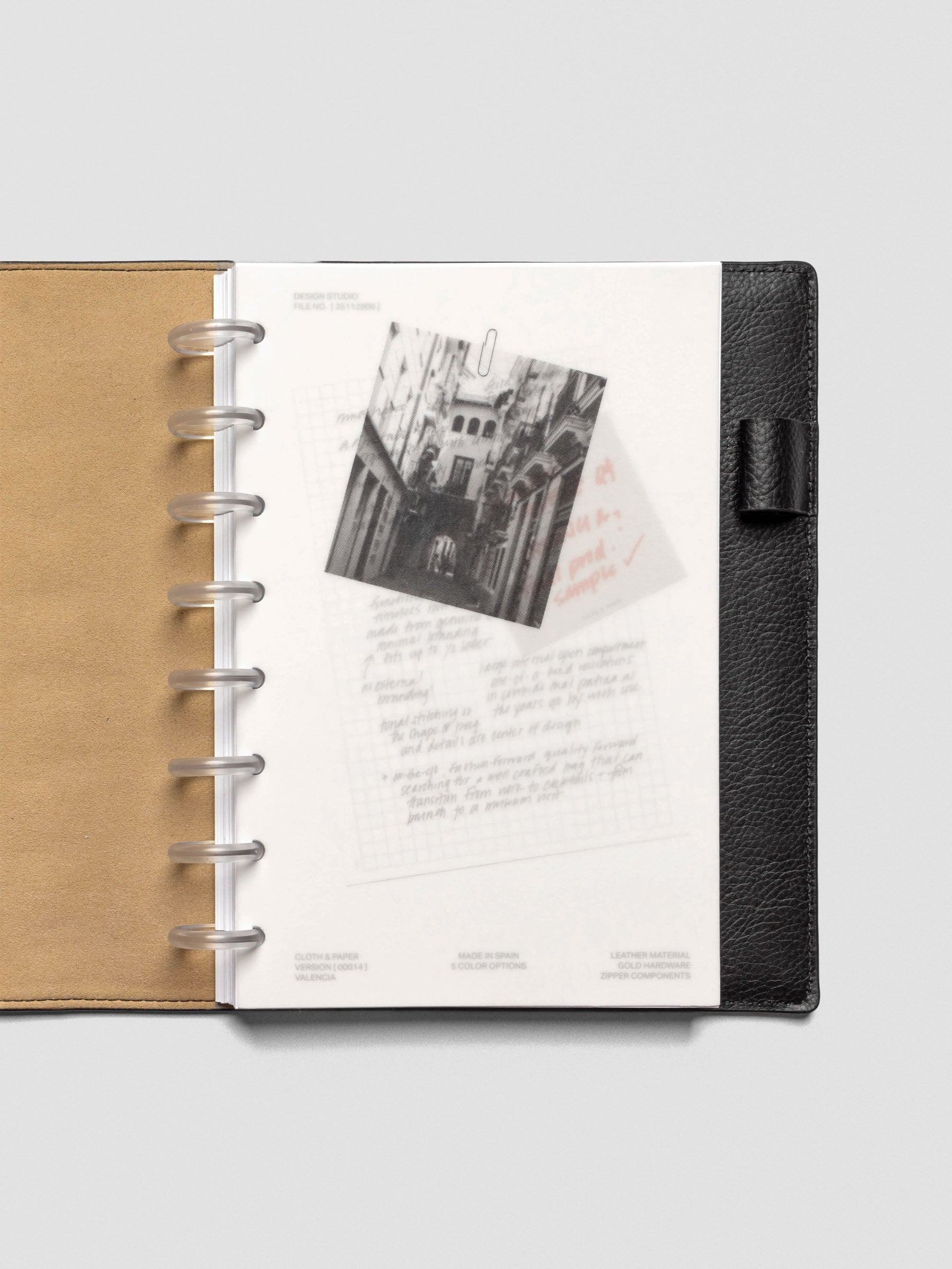 Half-letter Behind the Scenes Dashboard Duo insert in a black leather planner with tan interior. The vellum overlay shows a black-and-white photograph clipped above handwritten notes with a sticky note underneath.
