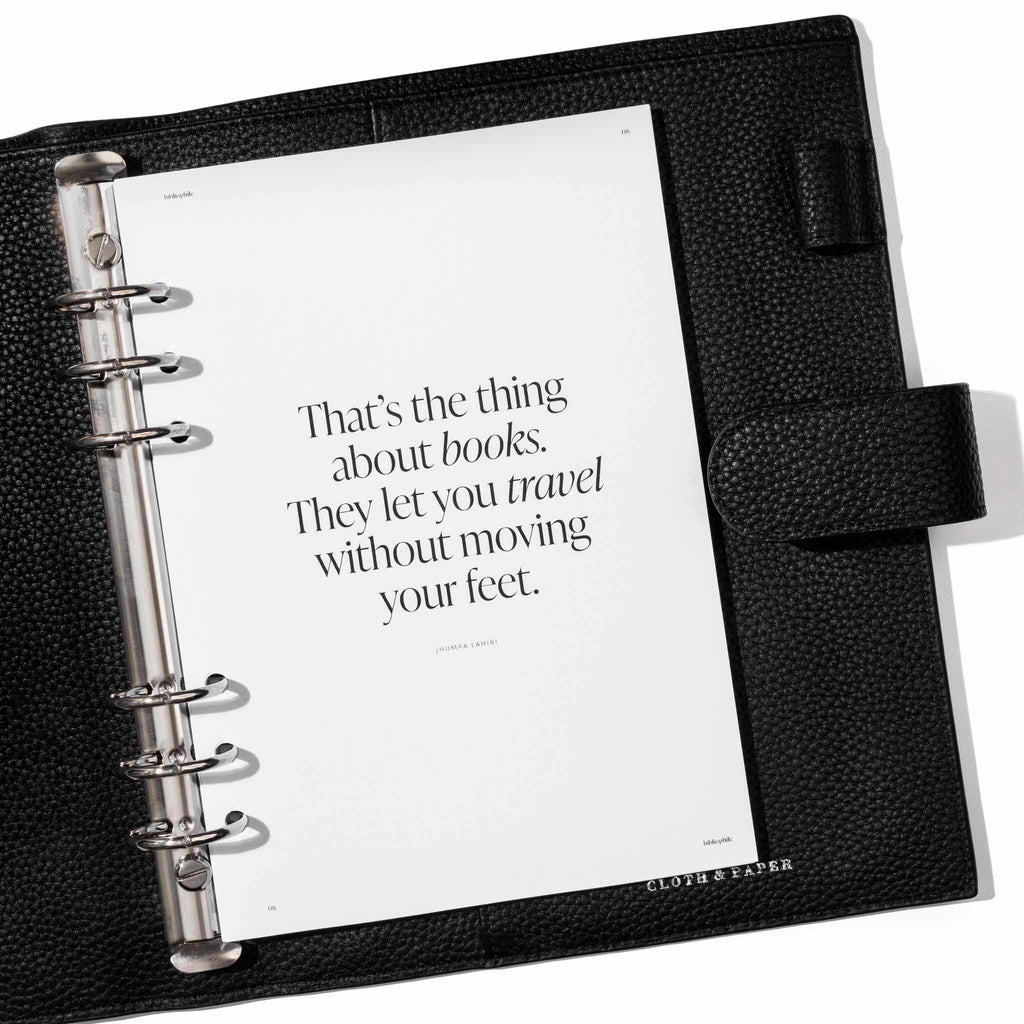 Insert in use inside a black leather planner. Page shown is the title page, reading "That's the thing about books. They let you travel without moving your feet."