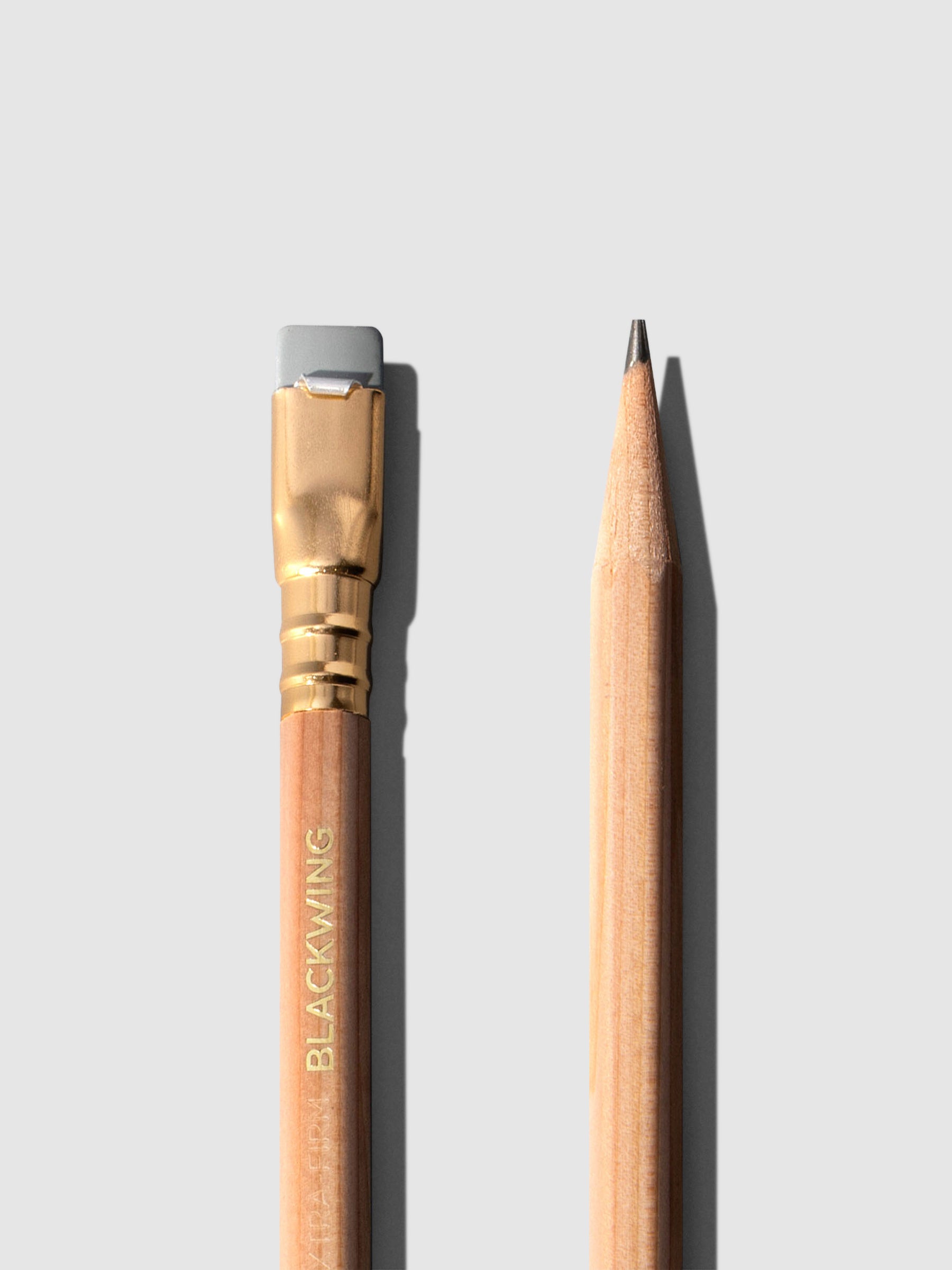 Closeup of two brown wooden pencils displayed on a neutral background. One is shown eraser side up, the other point side up.