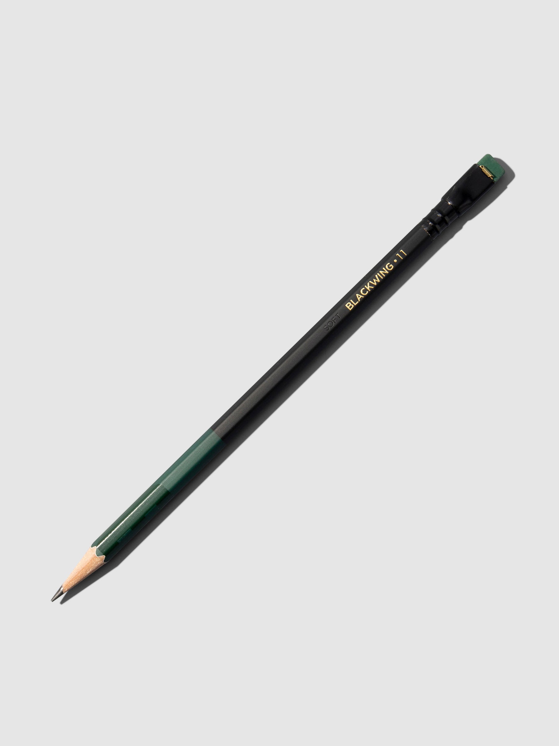 Green and black wooden pencil displayed on a neutral background.