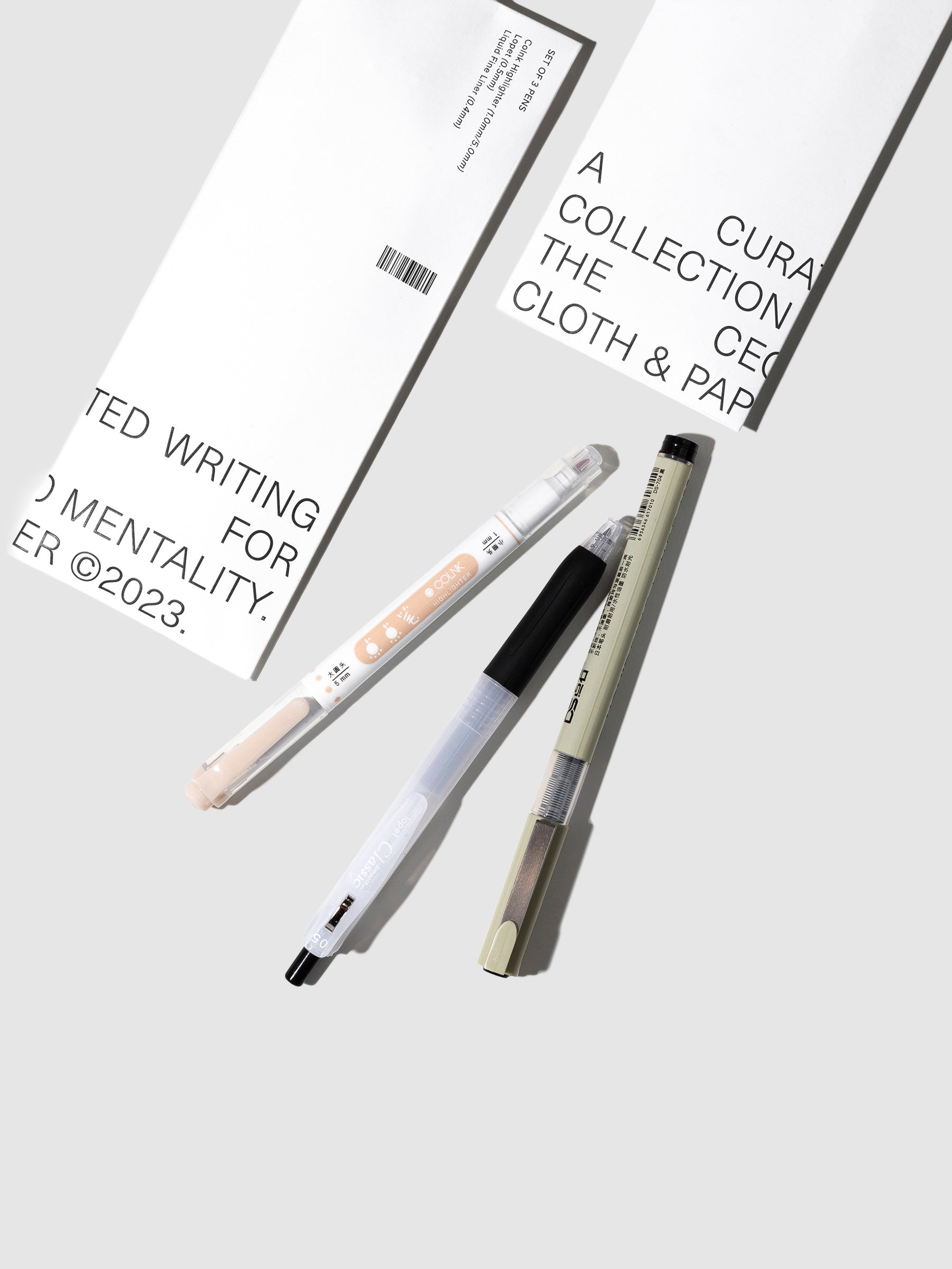 CEO Writing Collection, Cloth and Paper. Two pens, a highlighter, and the product packaging are displayed on a neutral background.
