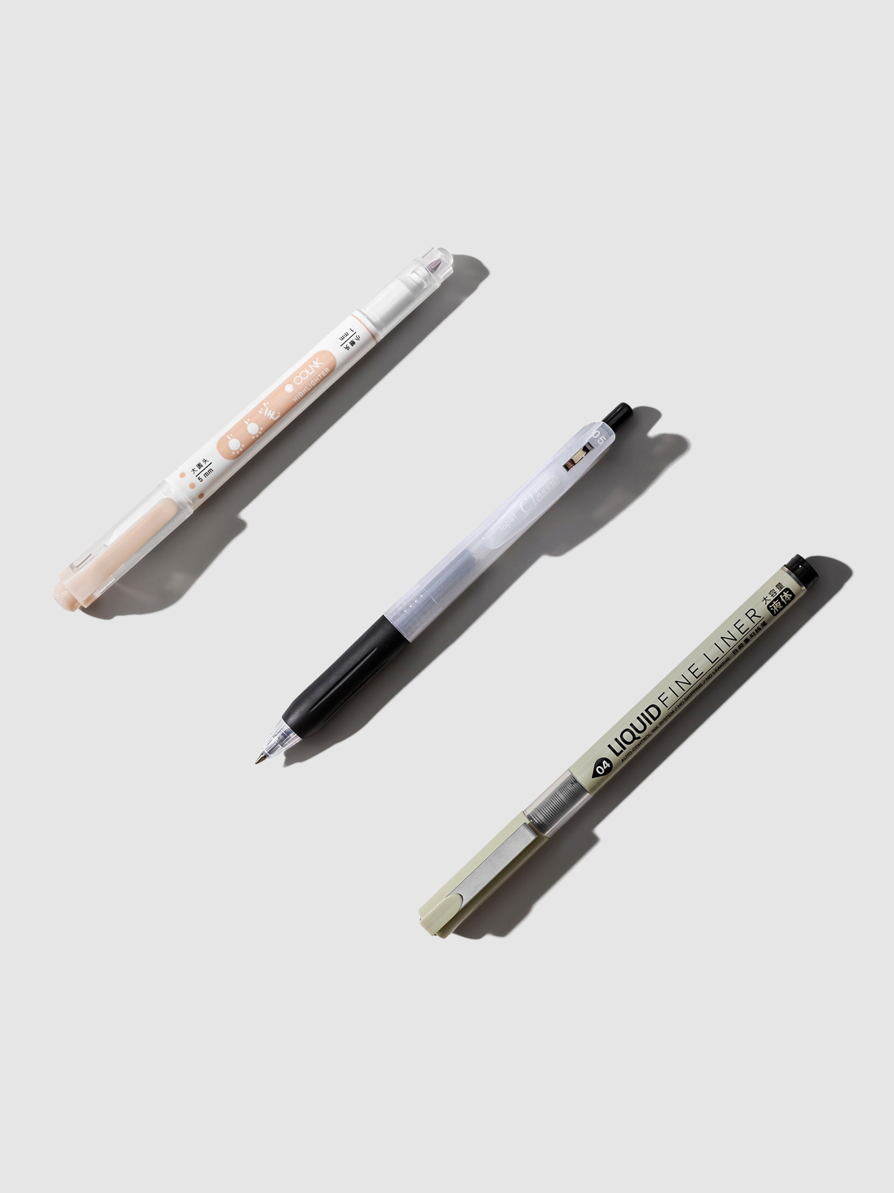 Two pens and a highlighter arranged together on a neutral background.