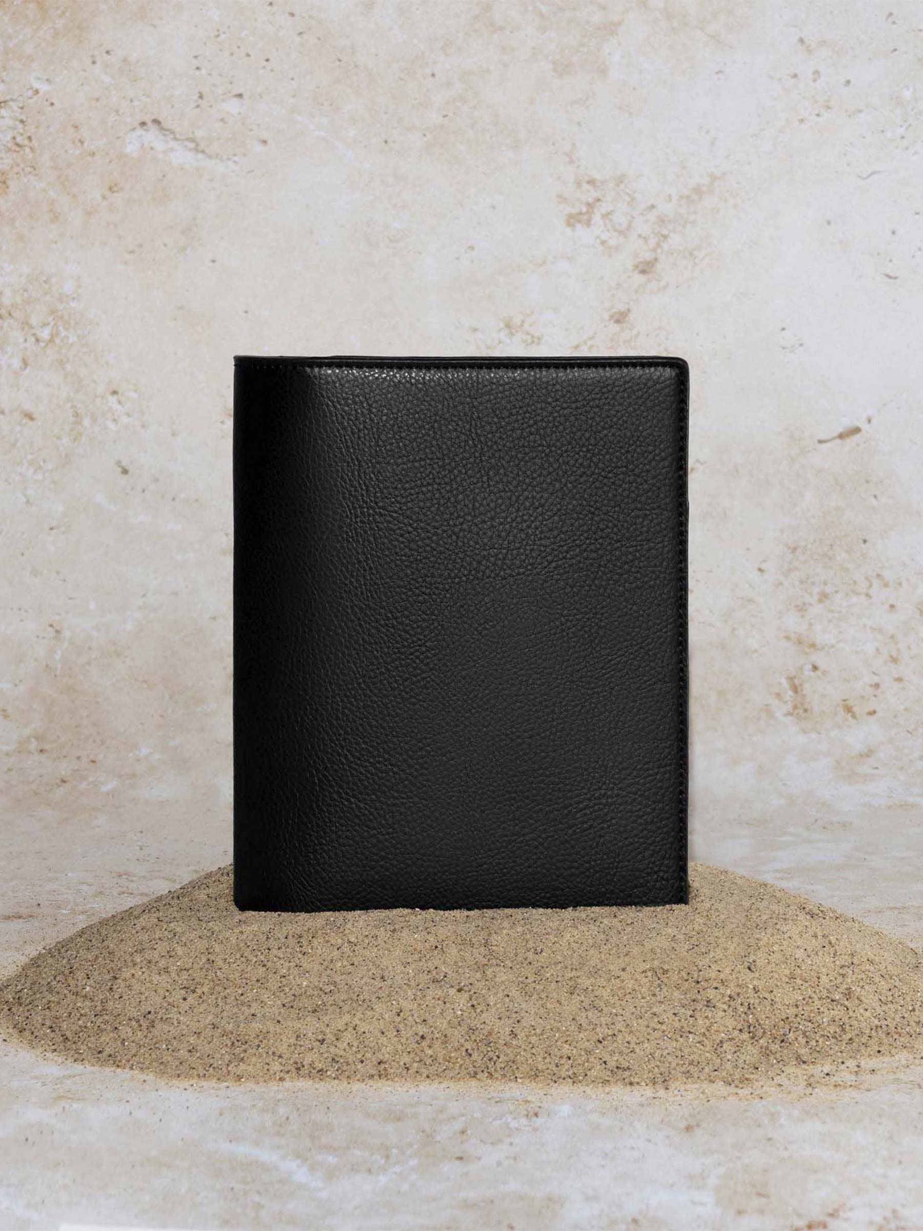 Cactus Vegan Leather Folio, CP Petite, Cloth and Paper. Folio displayed on a textured tan background, placed in a pile of sand. Color pictured is mesa black.