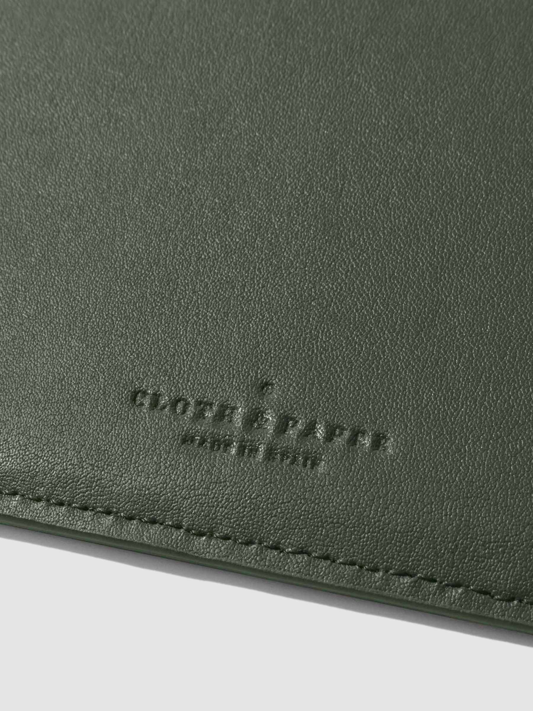 Closeup of valley green folio's textured vegan leather and stamped Cloth and Paper logo.