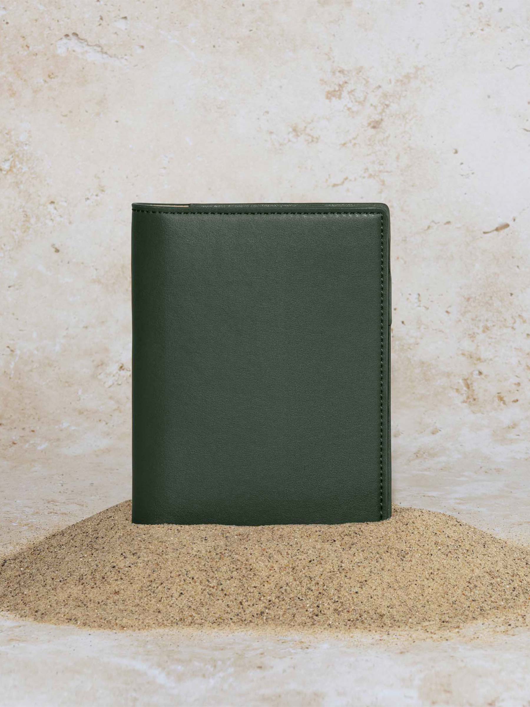 Folio displayed on a textured tan background, placed in a pile of sand. Color pictured is valley green. 