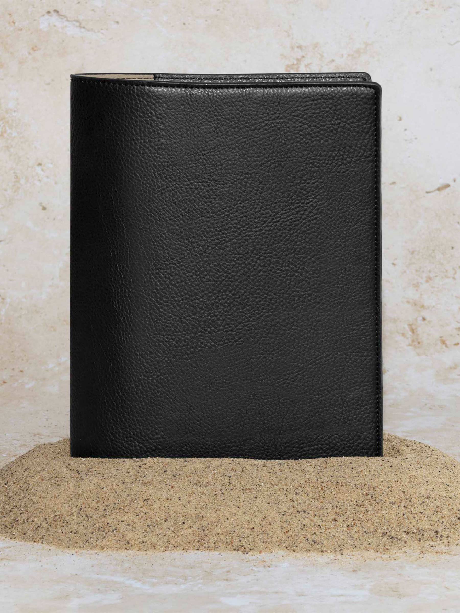Cactus Vegan Leather Folio, Half Letter, Cloth and Paper. Folio displayed on a textured tan background, placed in a pile of sand. Color pictured is mesa black.
