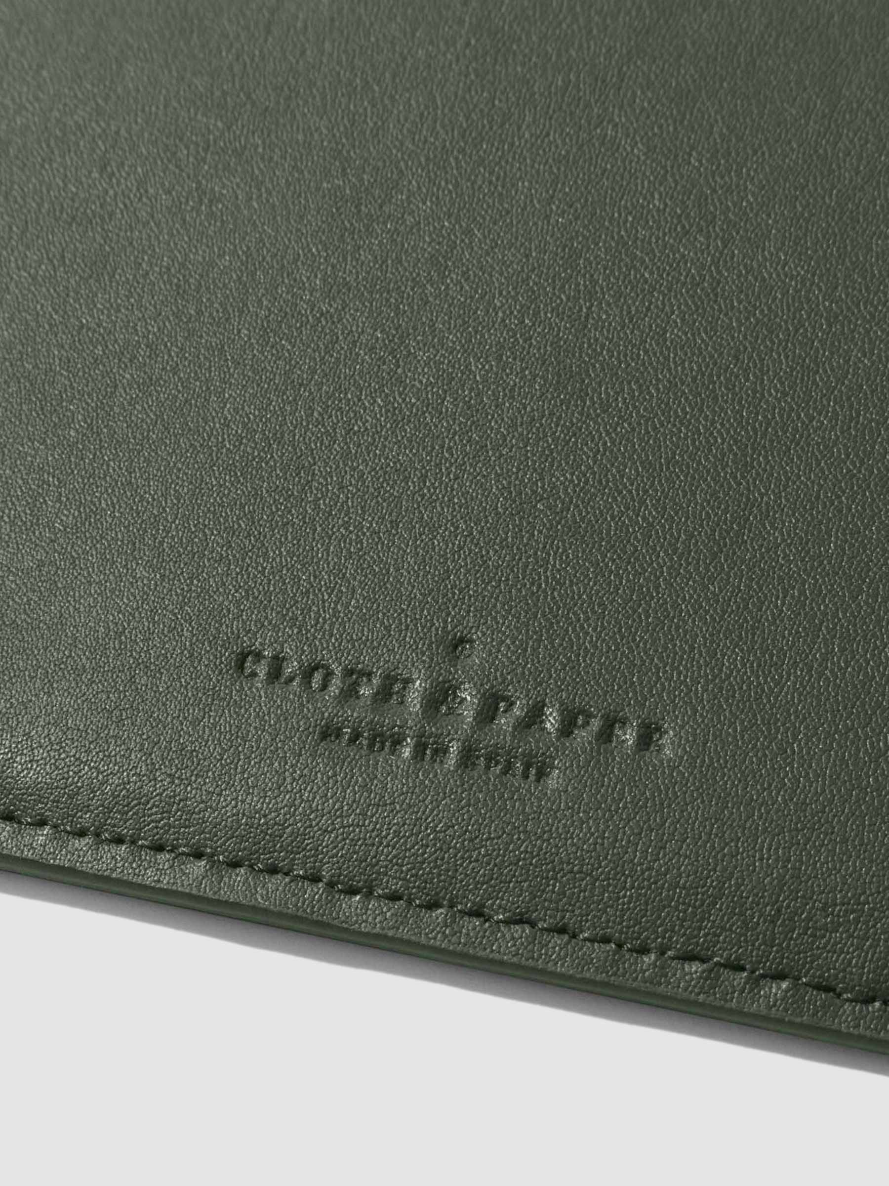 Closeup of valley green folio's textured vegan leather and stamped Cloth and Paper logo.