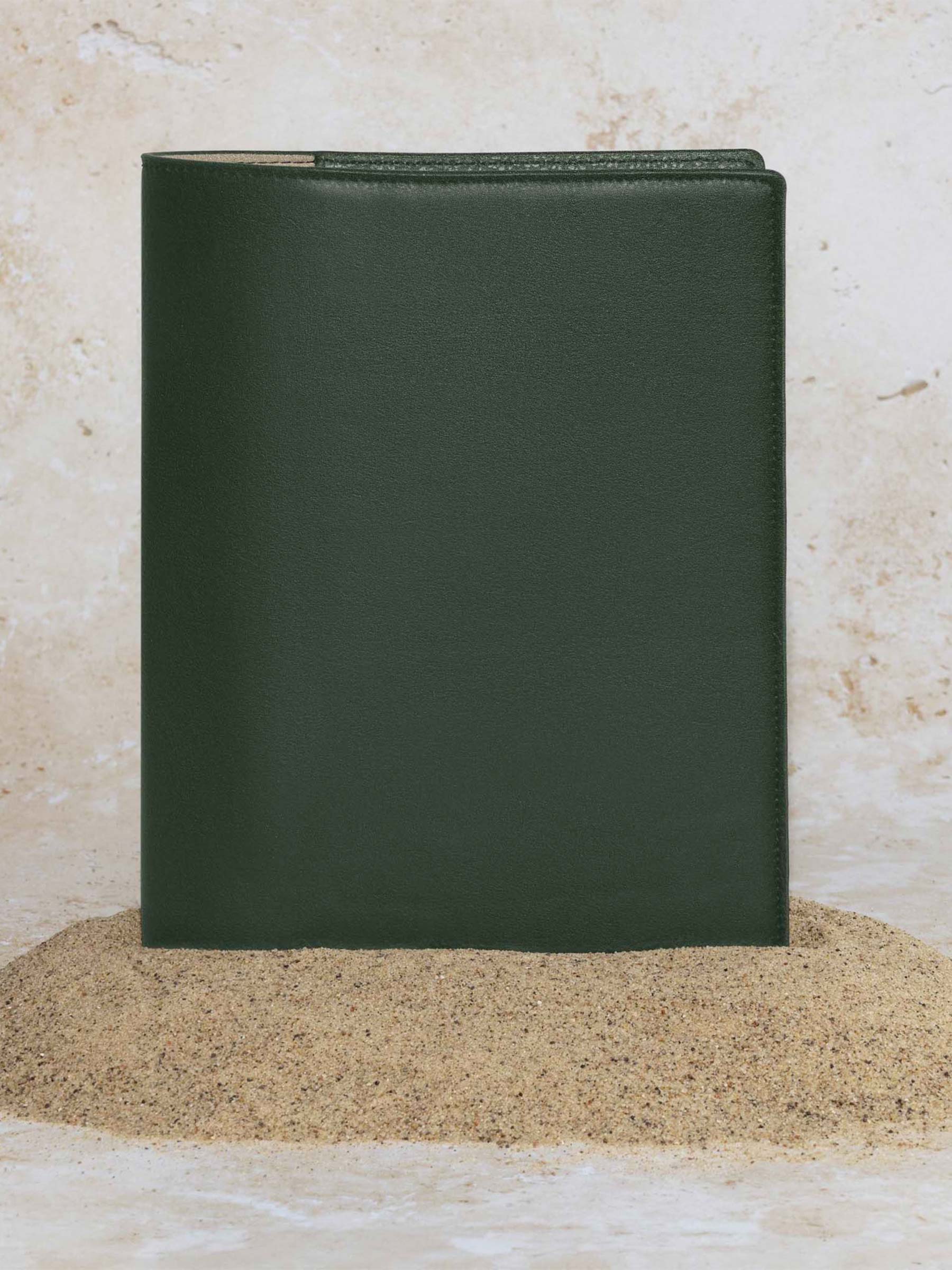 Folio displayed on a textured tan background, placed in a pile of sand. Color pictured is valley green.