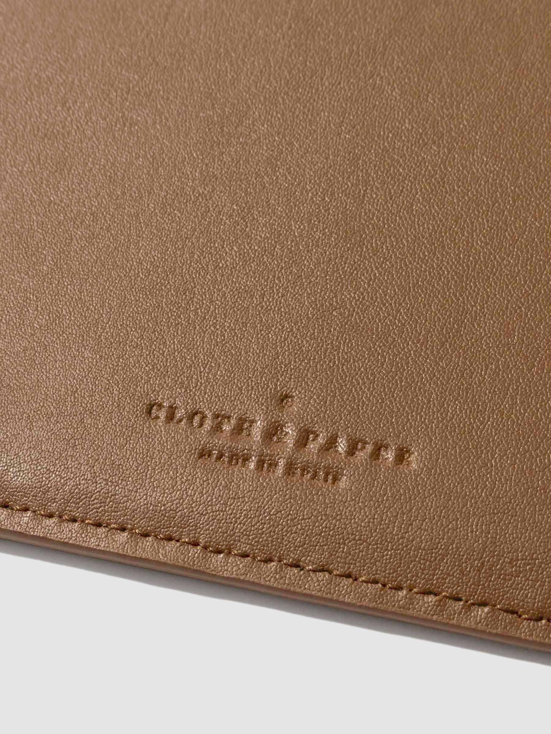 Closeup of clay brown folio's textured vegan leather and stamped Cloth and Paper logo.