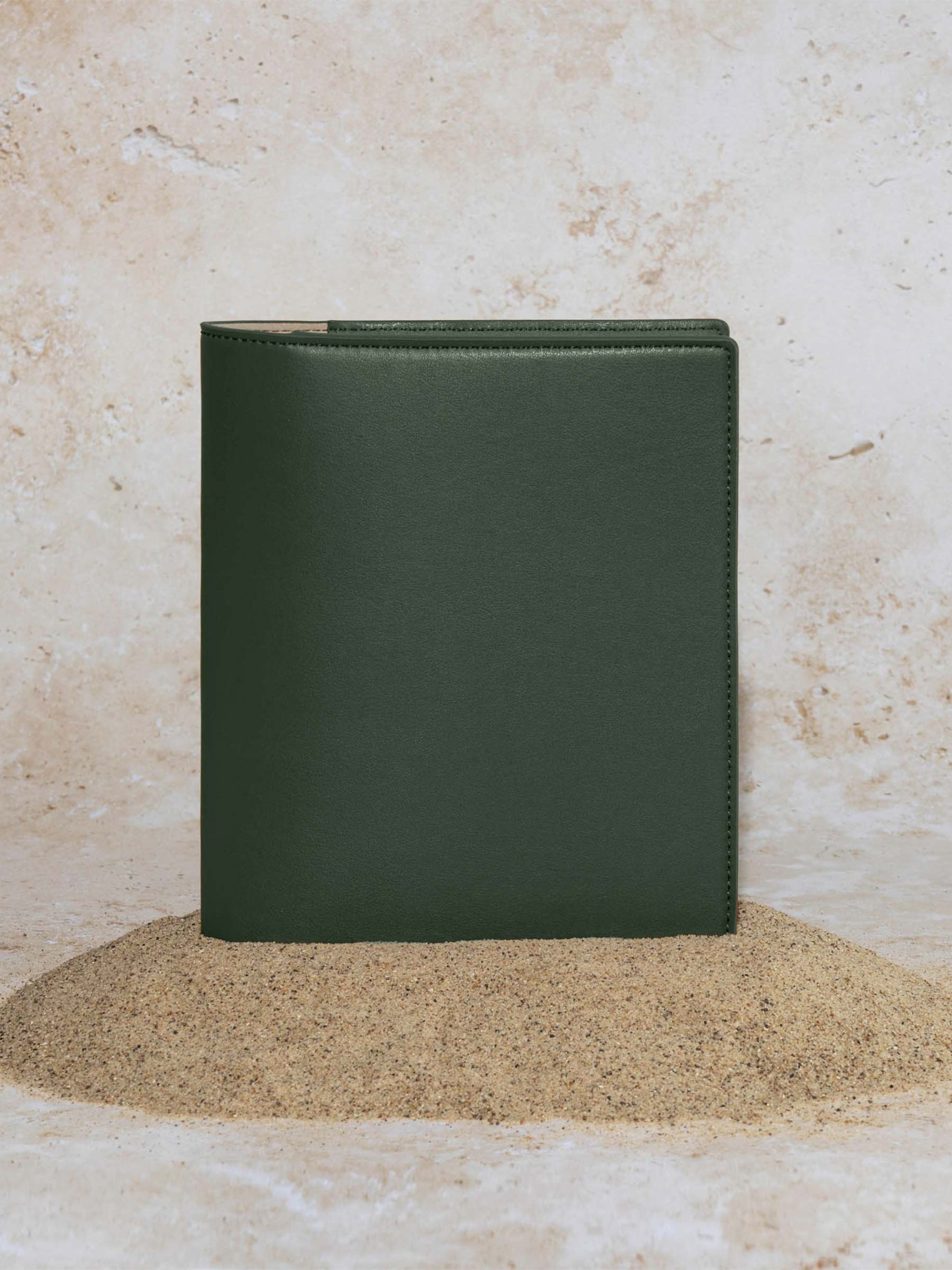 Folio displayed on a textured tan background, placed in a pile of sand. Color pictured is valley green.